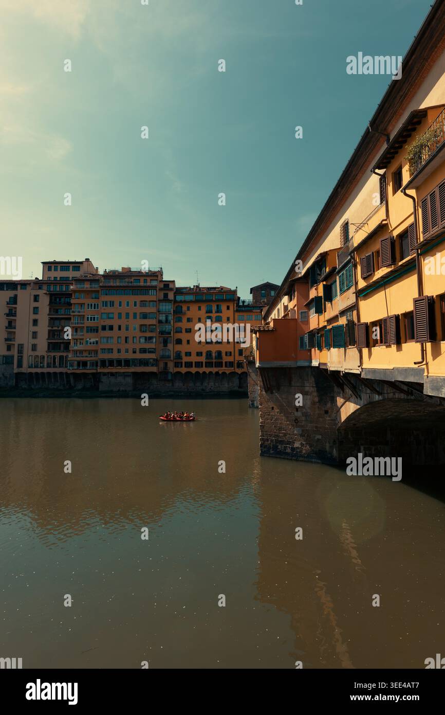Eine Aufnahme auf Augenhöhe, die die berühmte Brücke Ponte Vecchio in Florenz, Italien, mit ihren charakteristischen gelben Gebäuden und braunen Fensterläden festnimmt. Eine Gruppe von p Stockfoto
