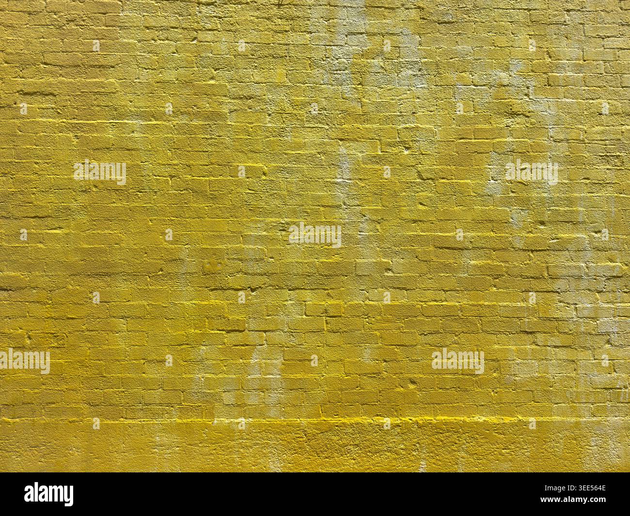 Ein Blick auf eine gelb gemalte Ziegelwand als Hintergrund. Stockfoto