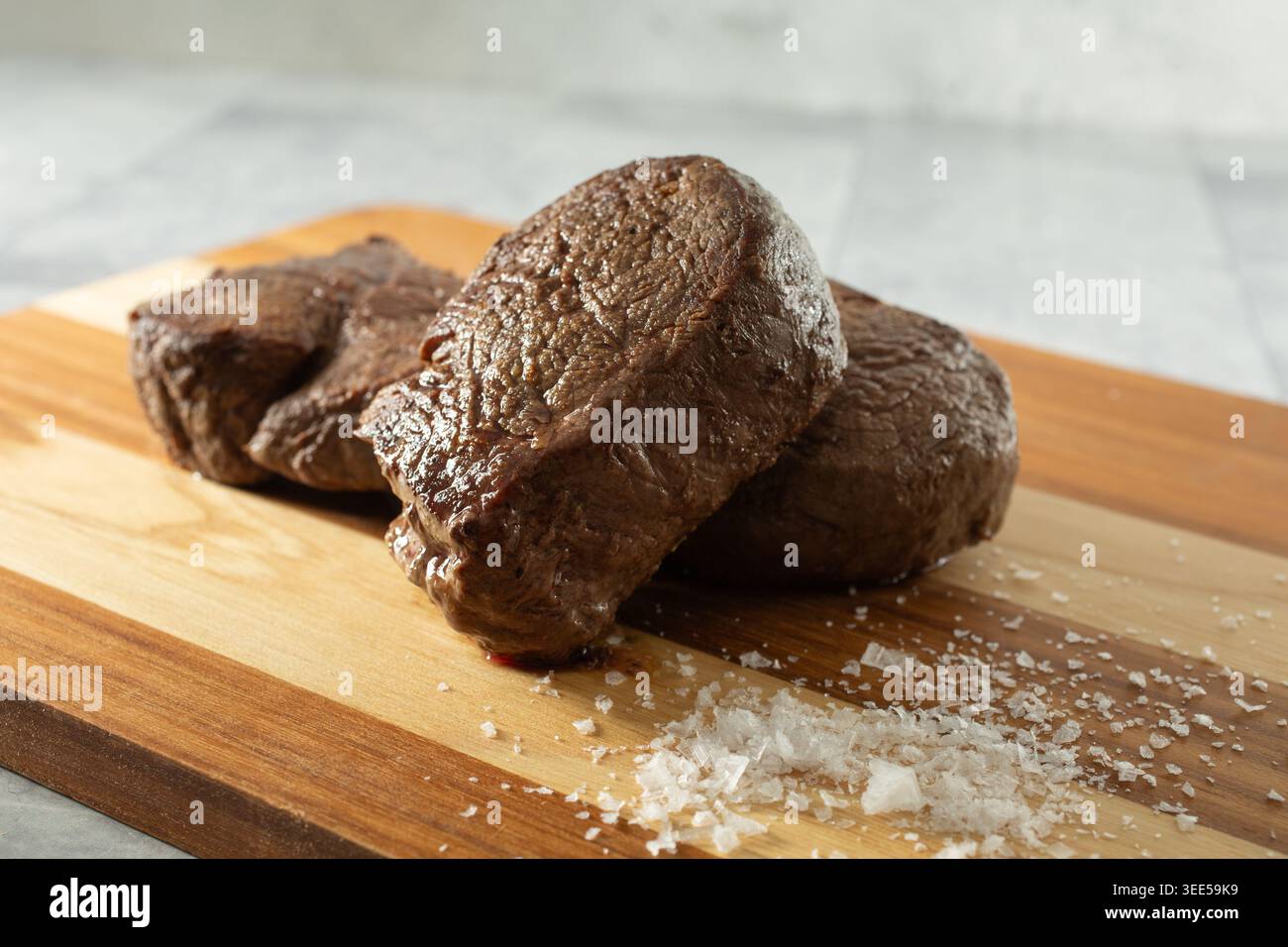 Blick auf einen Haufen gekochter Filet Mignon Steaks auf einem Holzbrett. Stockfoto