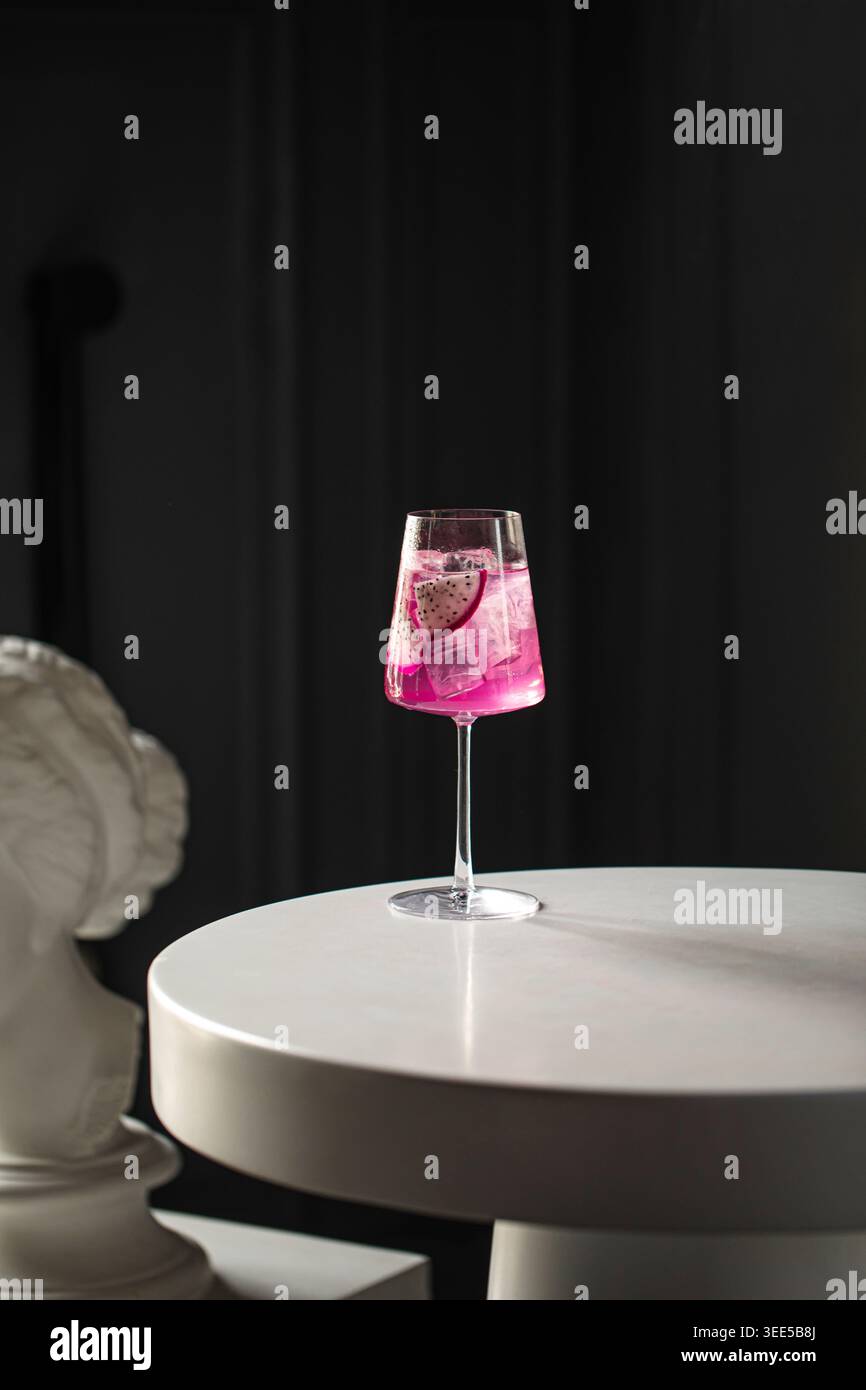 Rosafarbener Cocktail mit Obst auf dem Tisch und Statue Stockfoto