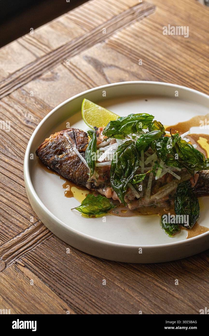 Gegrillter Fisch mit Kräutern und Limette auf Teller Stockfoto