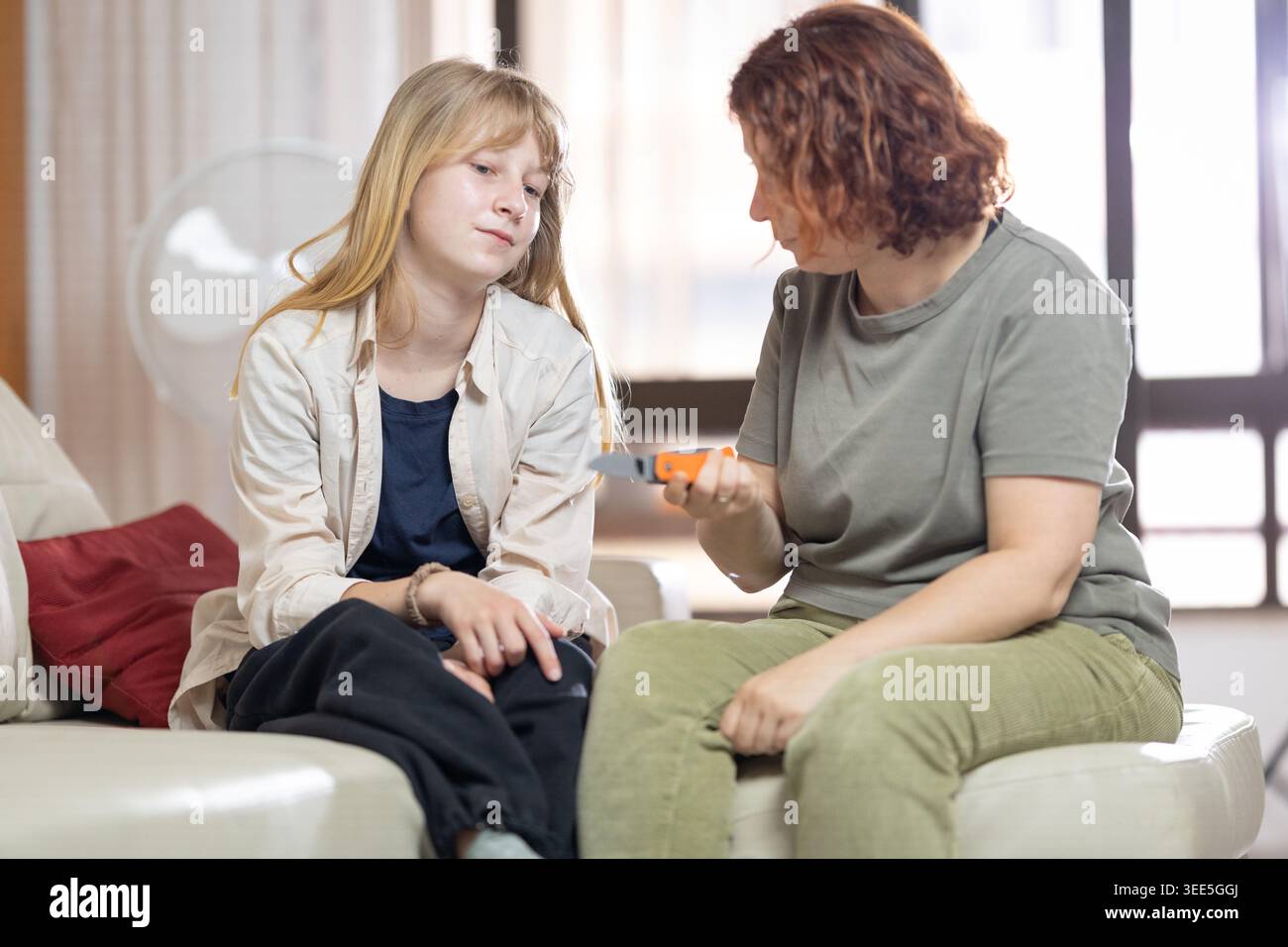 Mutter zeigt ein Gebrauchsmesser, um die Teenager-Tochter zu verärgern Stockfoto
