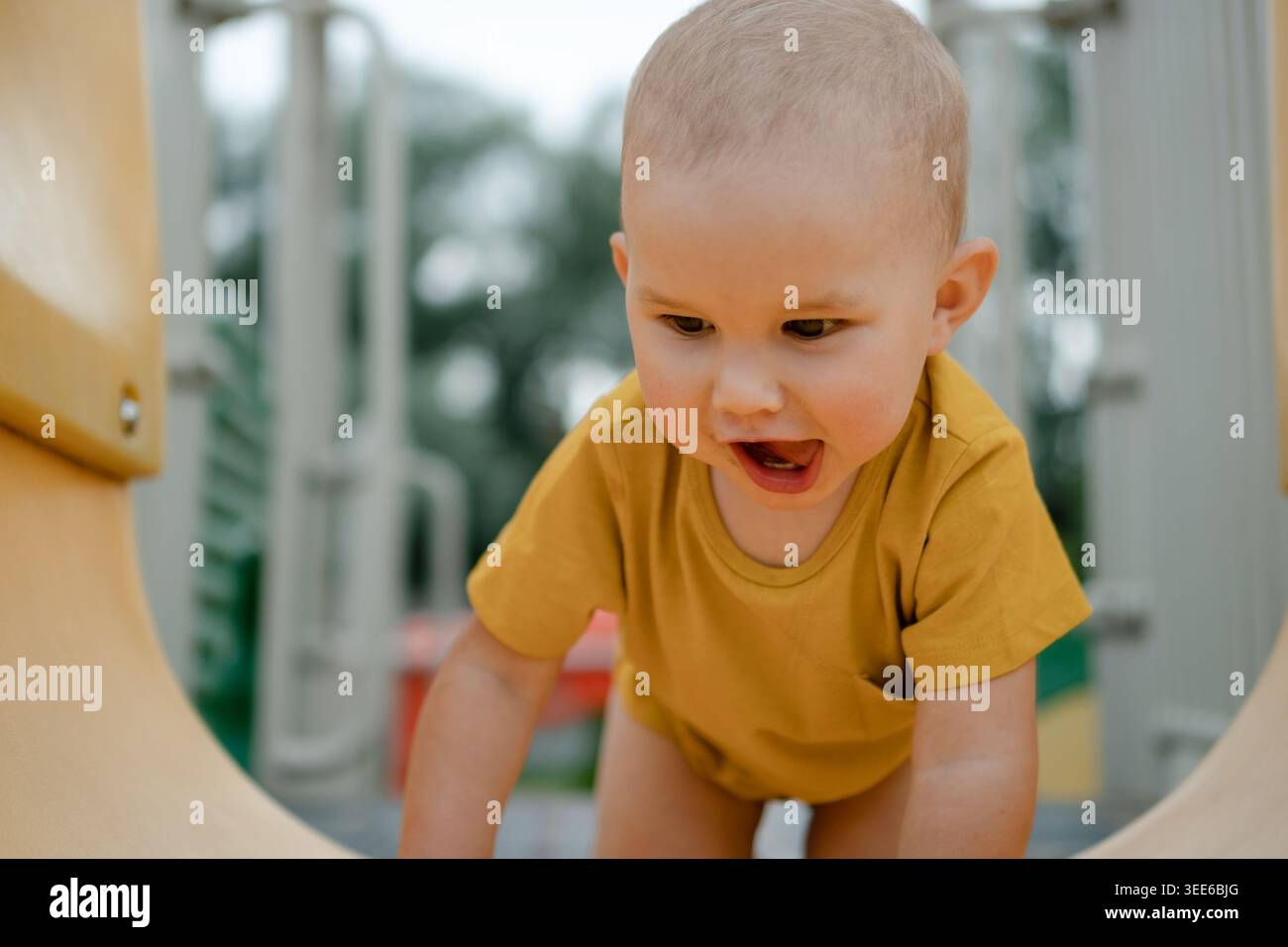 Fröhliches Baby, das die Arme weit ausbreitet und auf dem Spielplatz im Freien fröhlich ausdrückt. Entzücktes Kind feiert unbeschwerte Kindheitsfreiheit. Begeisterte Kleinkinder erleben pures Glück auf einem hellen Spielplatz Stockfoto