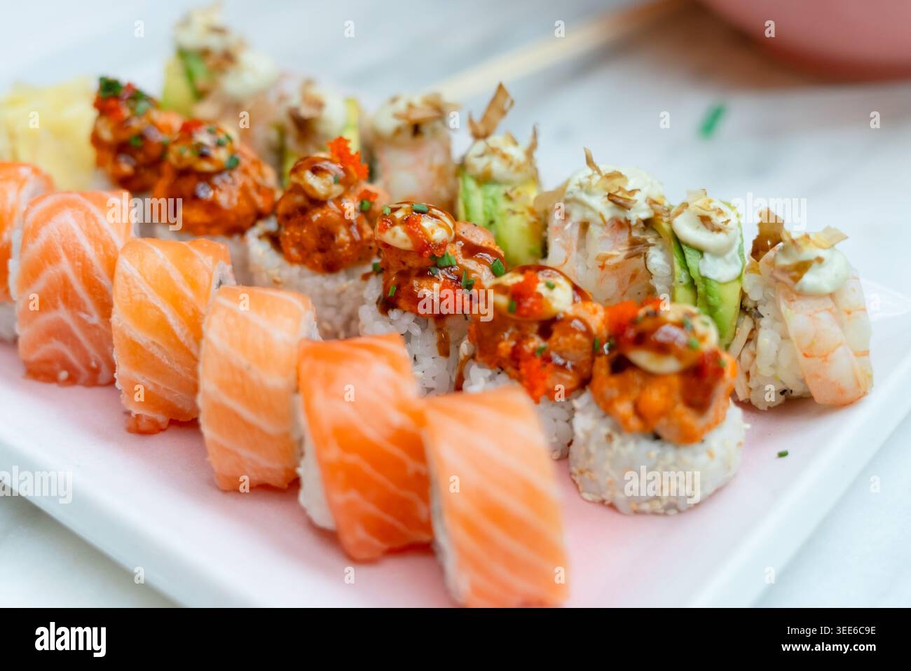Künstlerisches Sushi- und Sashimi-Arrangement auf weißem Hintergrund, das japanische kulinarische Ästhetik zeigt. Minimalistische Präsentation frischer Lachsnigiri mit elegantem Design. Raffinierte gastronomische Kunst Stockfoto