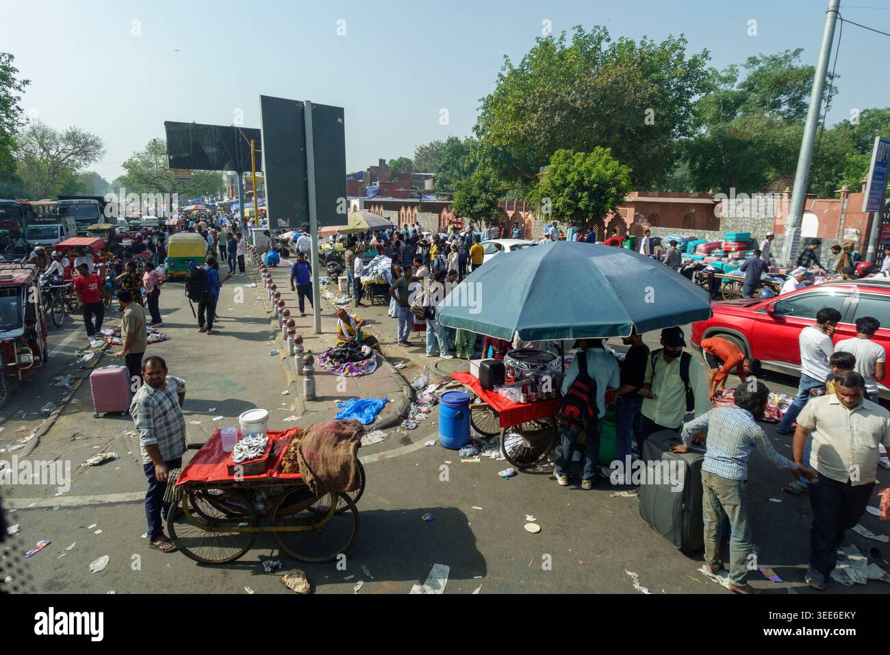 Geschäftige Straßenszene in Delhi in der Nähe des Red Fort mit Menschenmassen und Straßenverkäufern, die unter der Sonne auf mobilen Karren Waren verkaufen Stockfoto