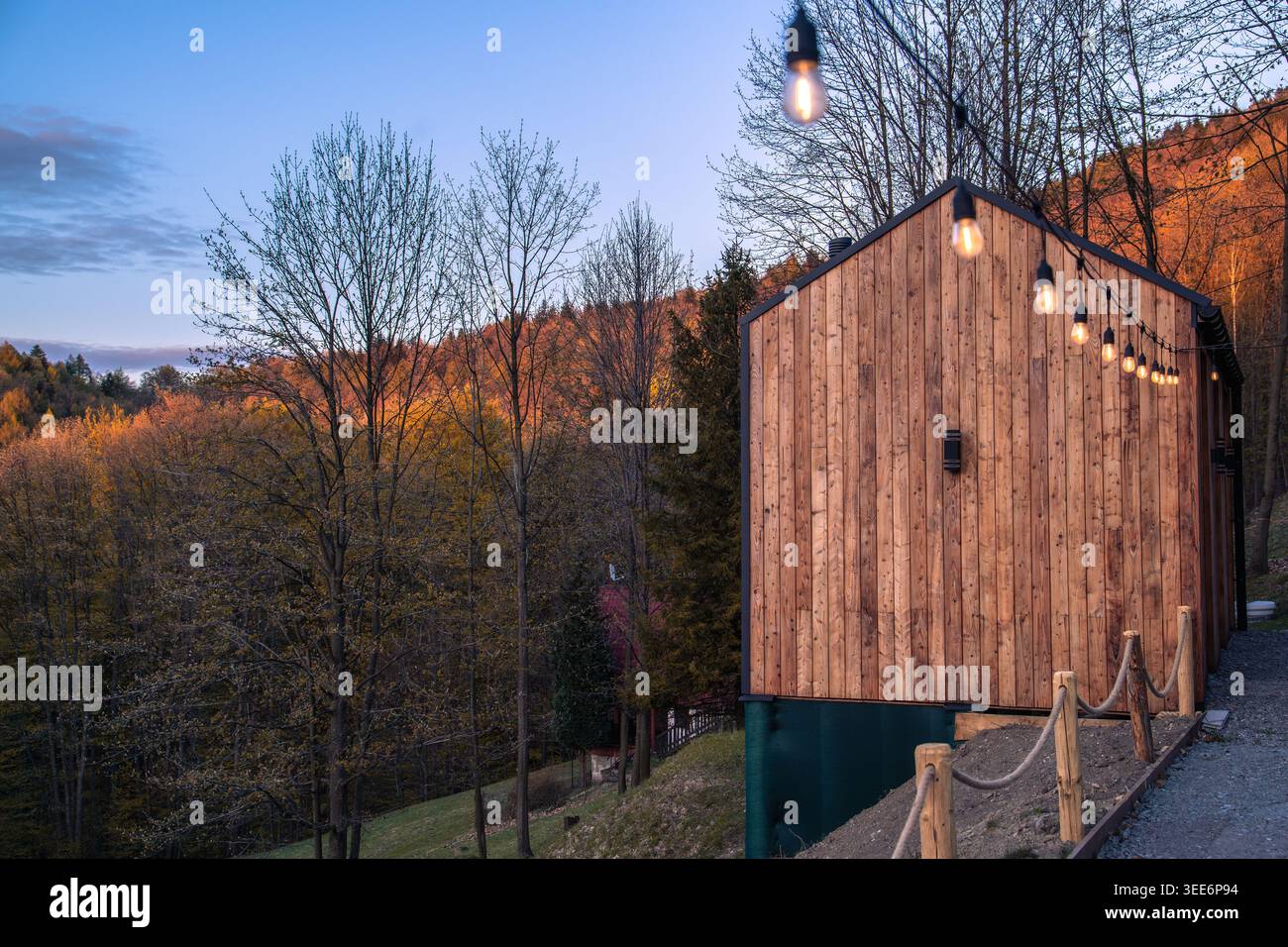 Gemütliches Holzhaus auf einem Hügel mit Glühbirnen dekoriert, Bergregion Reisekonzept Stockfoto
