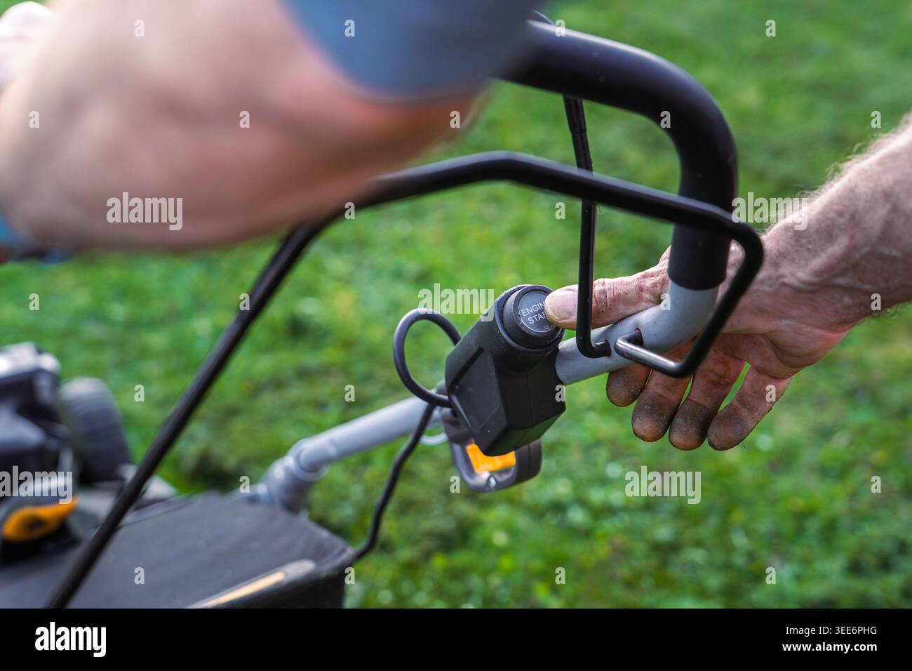 Nahaufnahme: Man drückt die Start-Taste am Rasenmäher-Motor Stockfoto
