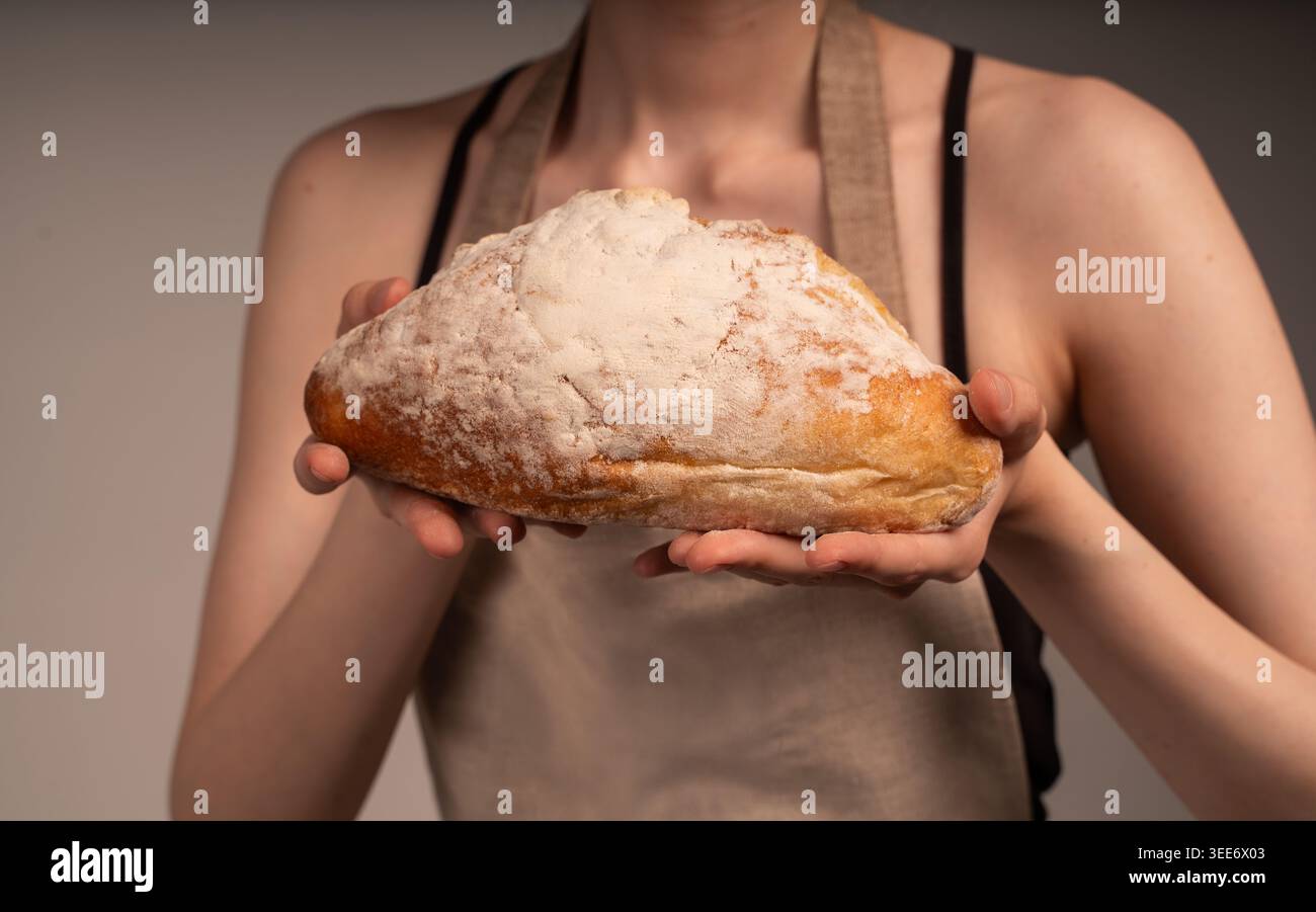 Baker hält frisches hausgemachtes, rustikales Sauerteigbrot mit einer mehlstaubten Kruste und präsentiert Backhandwerkskunst Stockfoto
