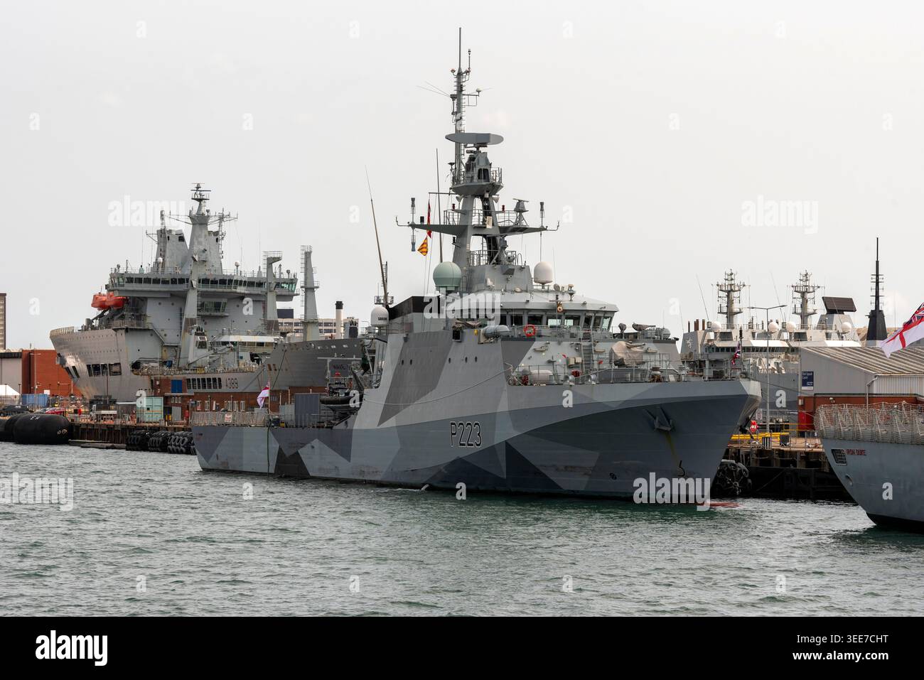 Portsmouth England Großbritannien. 18.08.2025. Ein modernes Kriegsschiff HMS TAMAR mit markantem Tarnmuster liegt an einem Dock neben anderen Marineschiffen Stockfoto