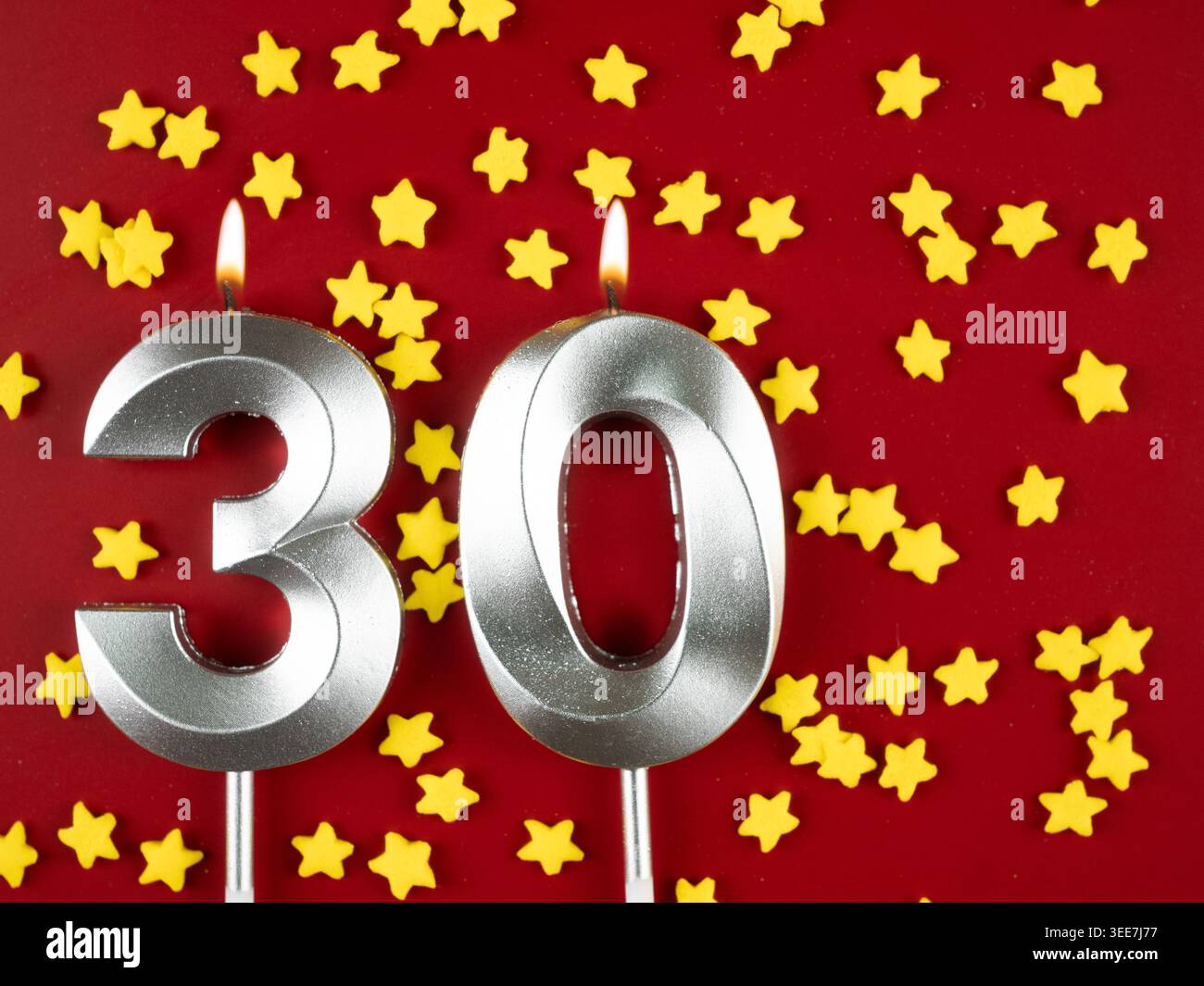 Konzept der Geburtstagsfeier und Jubiläumsfeier. Nummer 30 dreißig silberne Geburtstagskerze auf festlichem rotem Hintergrund. 30 Jahre Geburtstag. Stockfoto