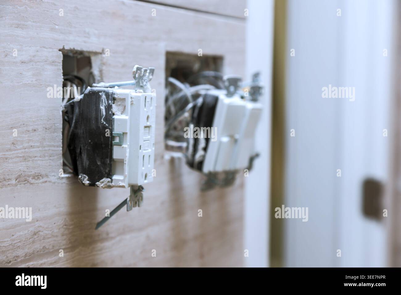 Zwei Steckdosen sind offen und Kabel sind freigelegt, was auf laufende Reparaturarbeiten hinweist Stockfoto