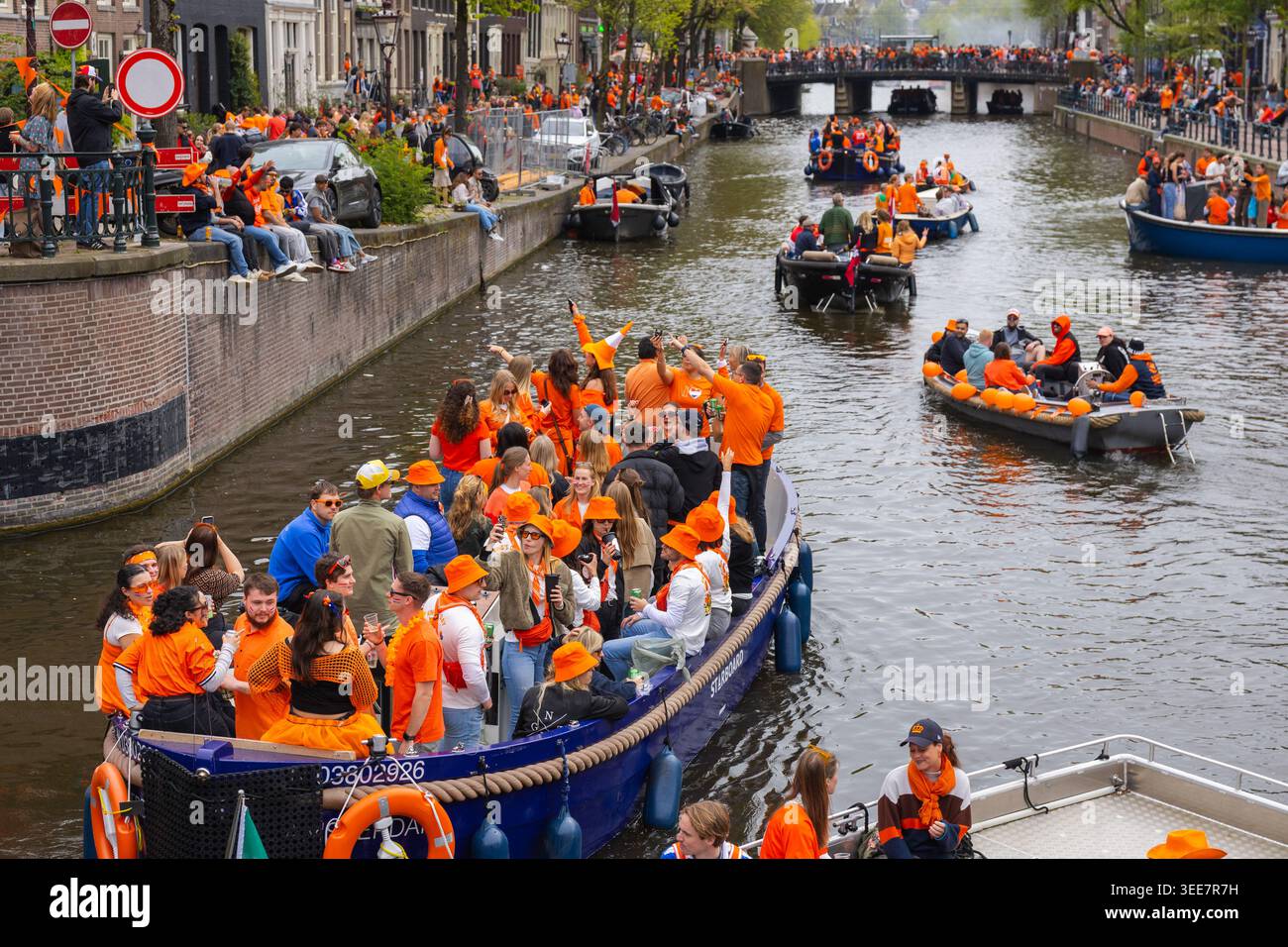 Amsterdam, Niederlande - 27. April 2026: Die Menschenmassen tragen orange und feiern auf Booten während des Königstages in Amsterdams Grachten mit lebhafter Atmosphäre und Spaß Stockfoto