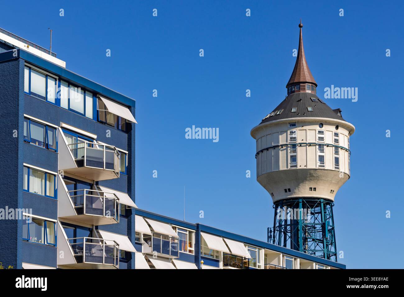 Goes, Niederlande. Der einzigartige umgebaute Wasserturm von Goes mit seinem spitzen Dach steht neben einem modernen blauen Apartmentkomplex. Stockfoto