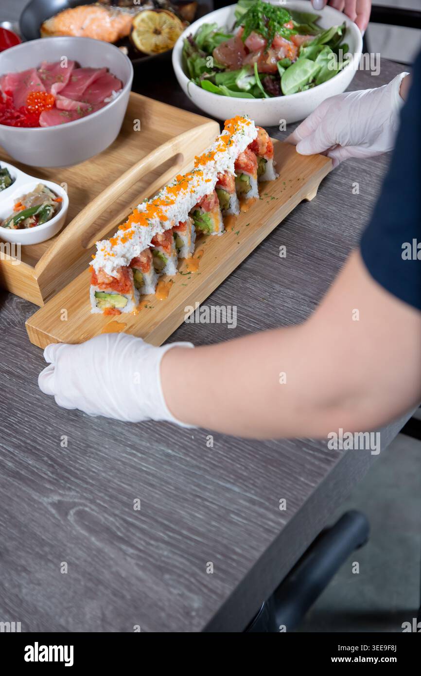 Ein japanischer Restaurantangestellter, der einen Sushi-Rollteller ablegt. Stockfoto