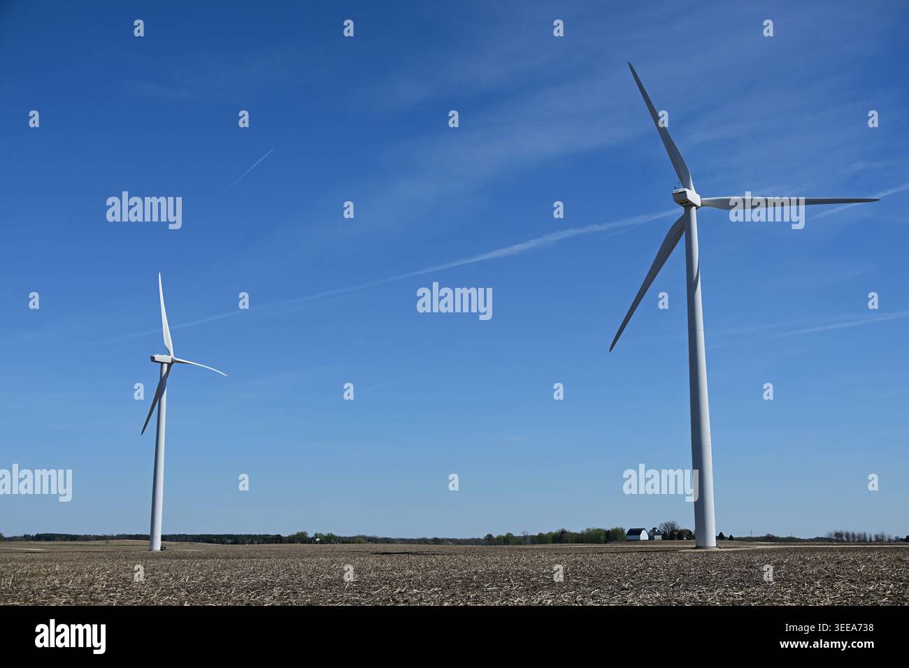 Shabbona, Illinois, USA. Zwei große Windturbinen erheben sich im Frühjahr auf einem großen Bauernhof im Norden von Zentral-Illinois über einem noch ruhenden Feld. Stockfoto