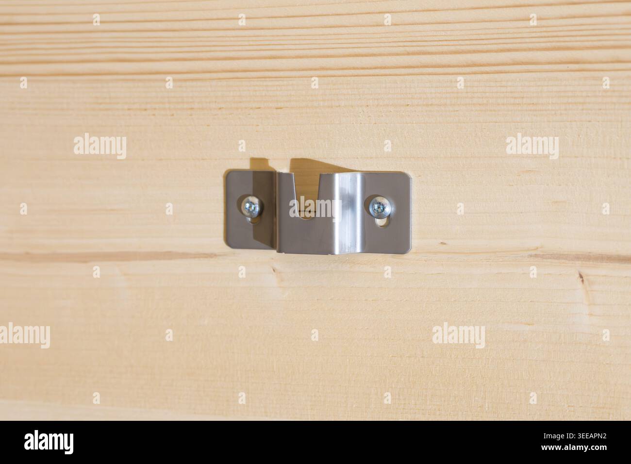 Montage an einer Holzwand in Nahaufnahme. Metallteil zum Aufhängen eines Heizelements an der Wand in einem Wohngebäude. Verschraubter Halter in einem Raum. Stockfoto