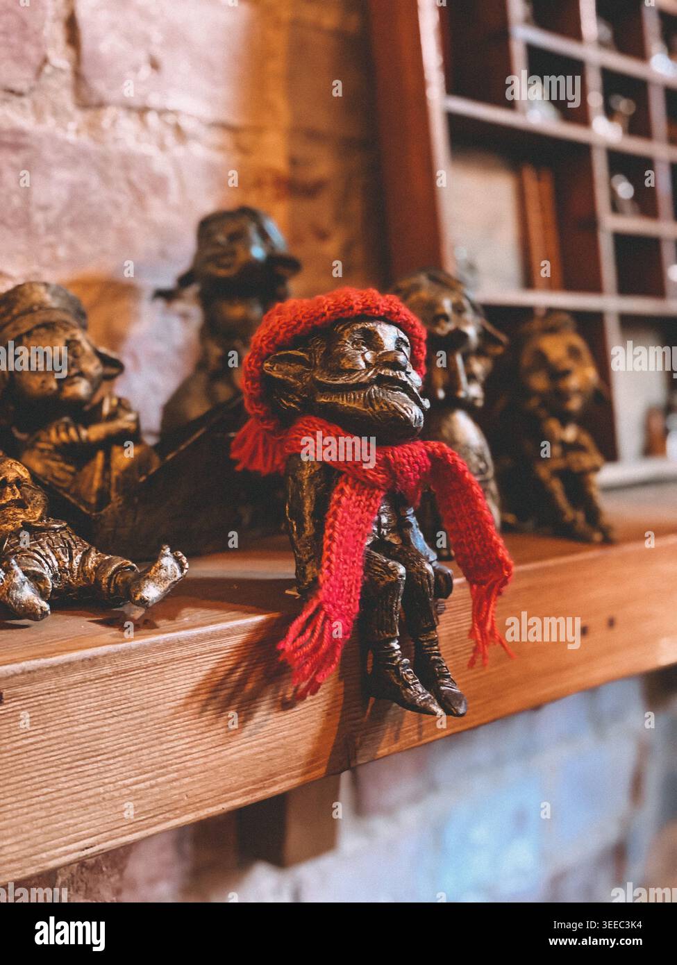 Kleine dekorative Figuren auf Holzregal, warmes Licht, gemütliche Lifestyle-Szene im Innenraum - Smartphone-aufgenommenes Stockfoto