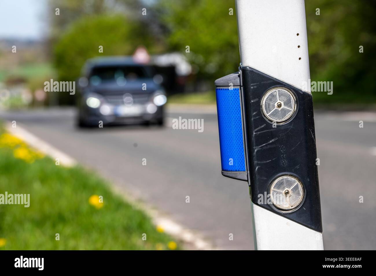 Straßenmarkierungspfosten auf einer Landstraße markieren den Fahrbahnrand und dienen insbesondere im Dunkeln der visuellen Orientierung durch Reflektoren; die blaue r Stockfoto