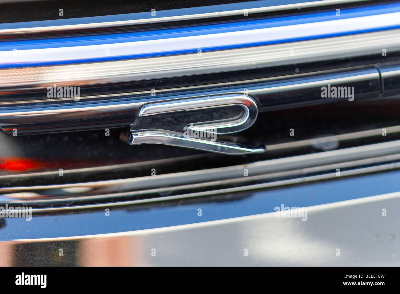 Verchromtes Emblem am Kühlergrill eines modernen Fahrzeugs mit blauen Akzenten Stockfoto