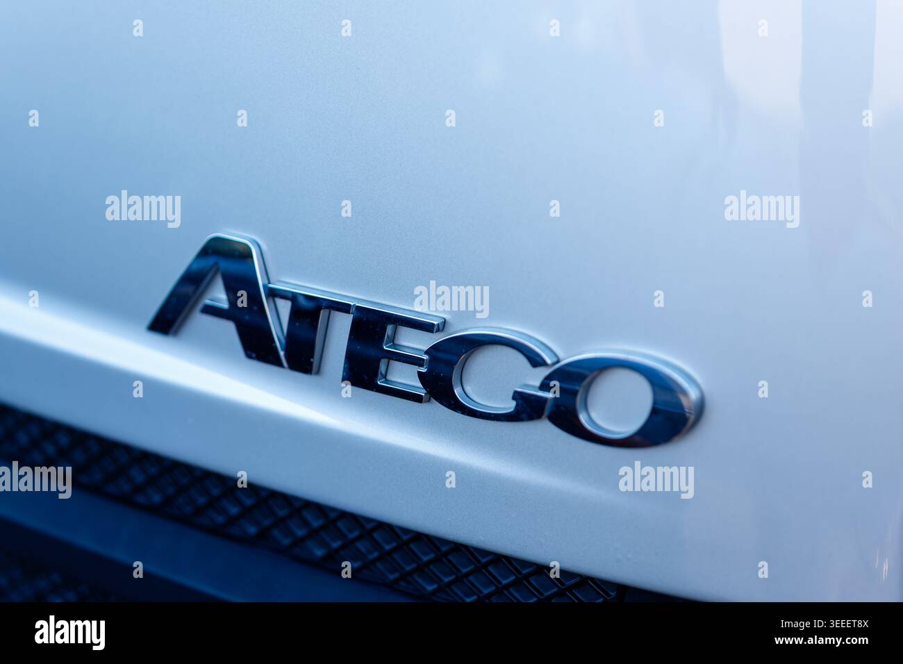 Nahaufnahme des glänzenden Chrom-atego-Emblems auf einer weißen fahrzeugoberfläche, das das Fahrzeugbranding zeigt Stockfoto