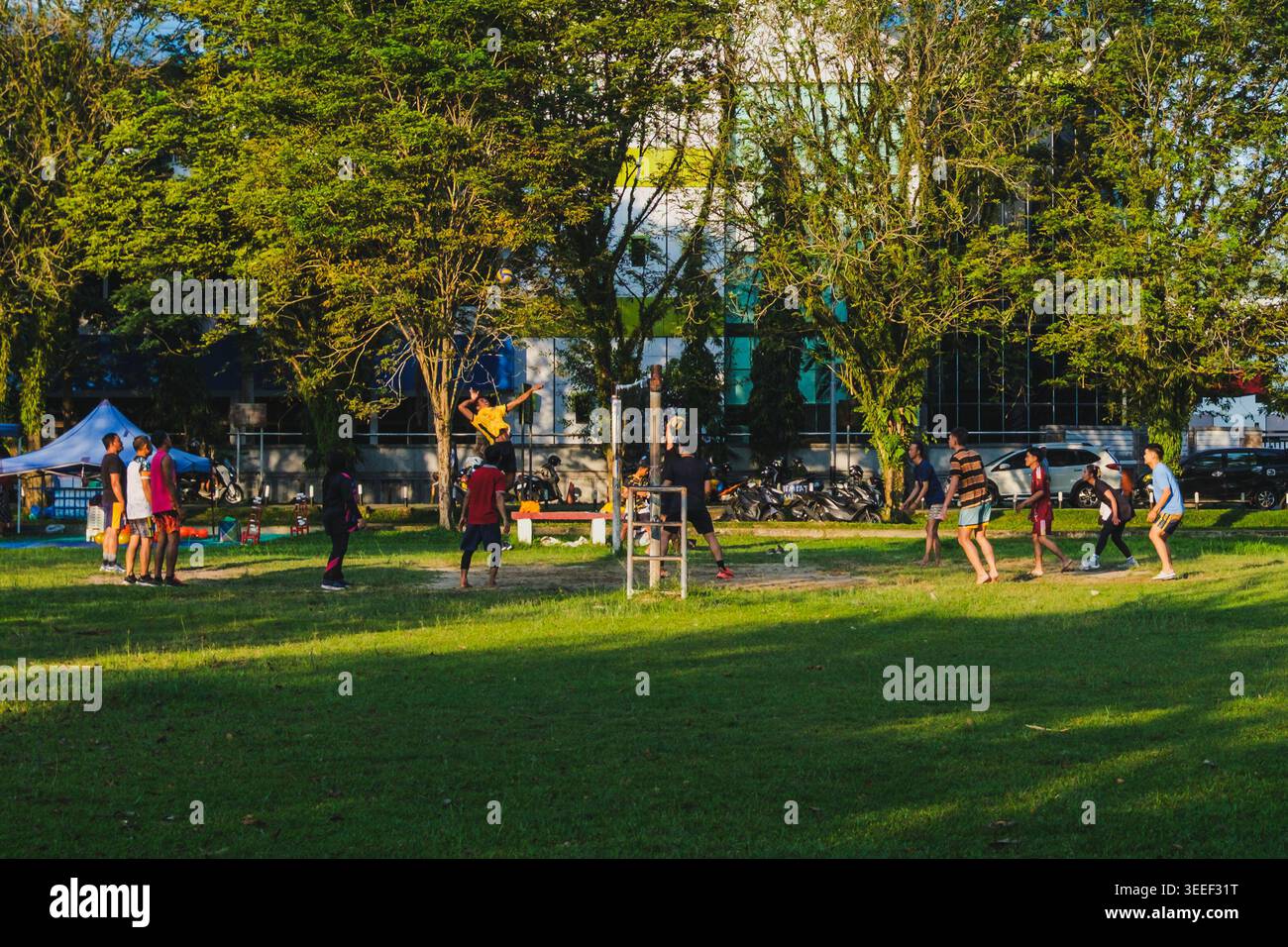 Balikpapan, Indonesien - 24. April 2026. Eine Gruppe junger Leute spielt Volleyball auf einem Rasenplatz in einem öffentlichen Park. Stockfoto