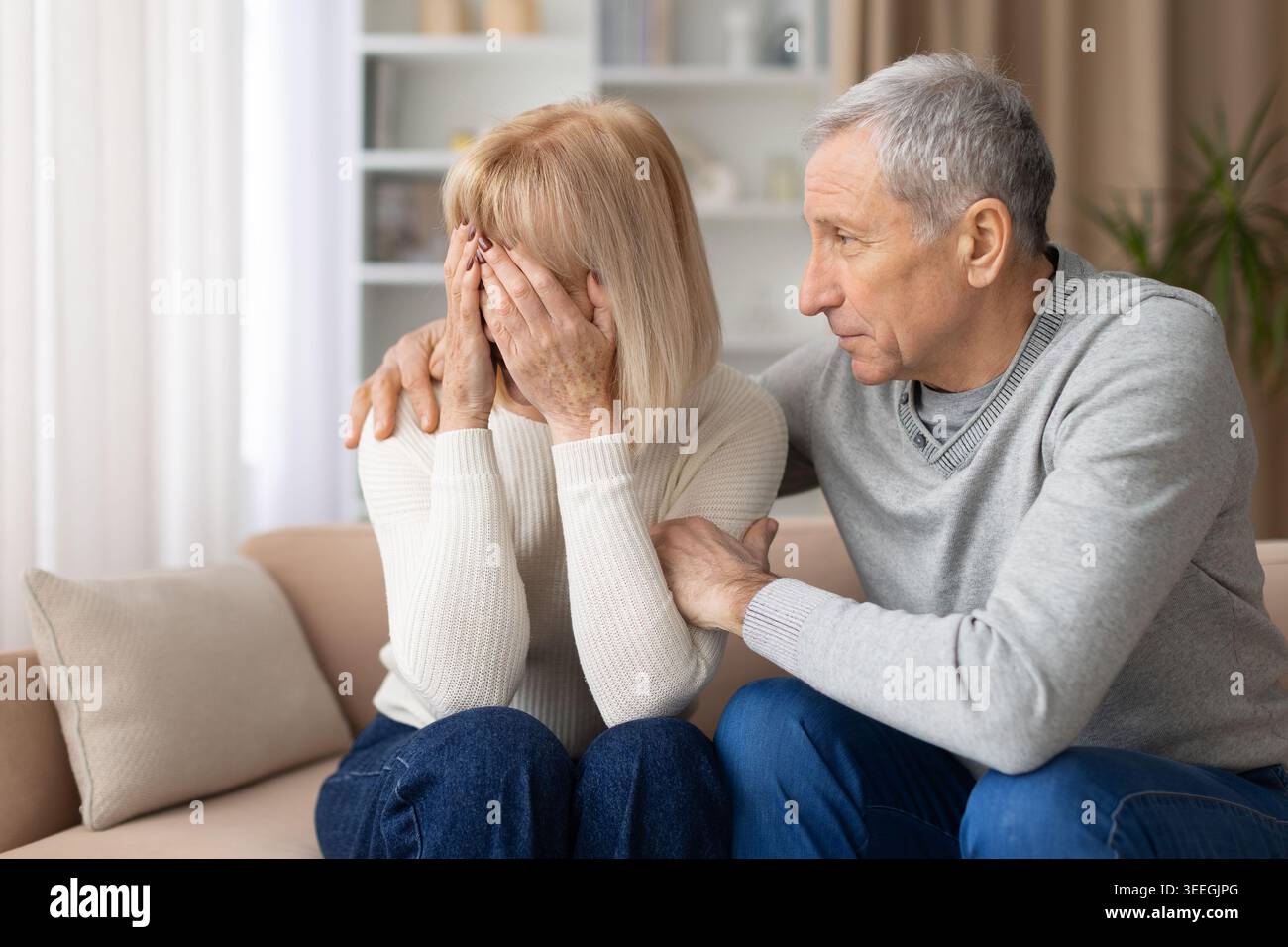 Reifer Mann tröstet verärgerte ältere Frau zu Hause und zeigt emotionale Unterstützung Stockfoto