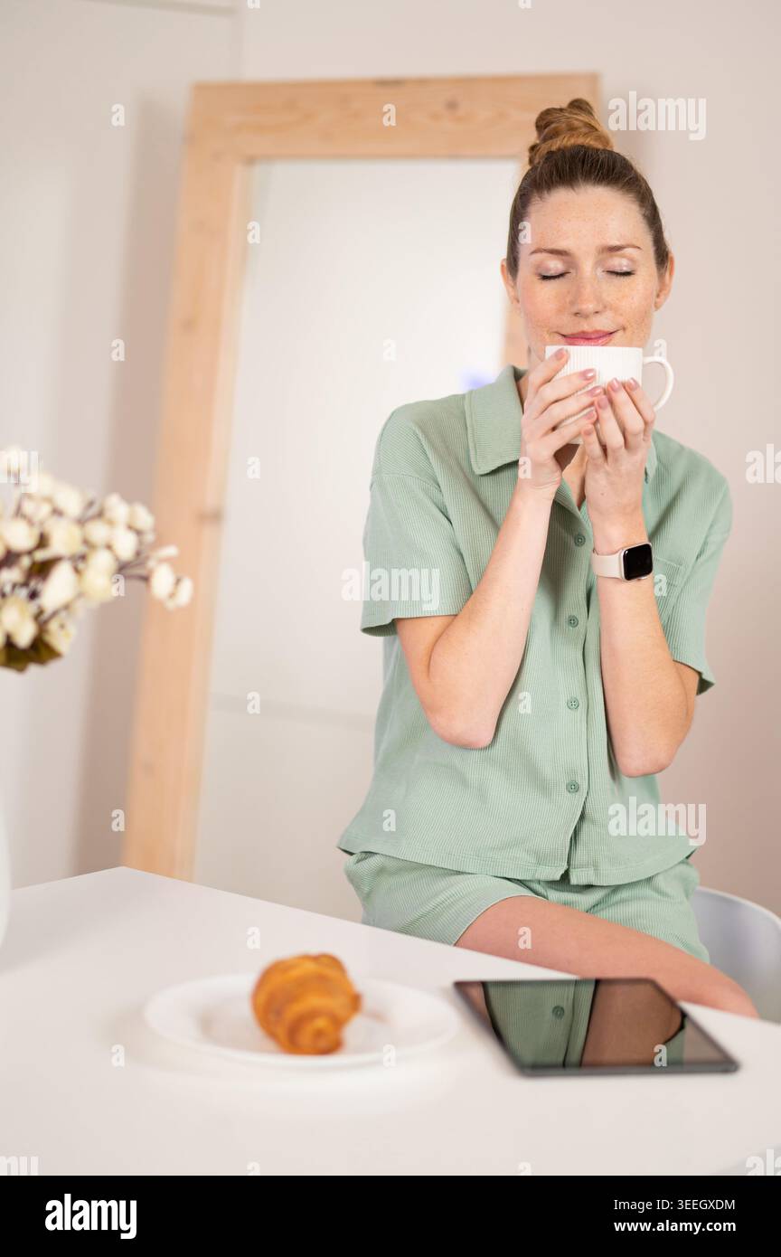 Süße junge Frau, die Kaffee riecht, mit geschlossenen Augen Stockfoto