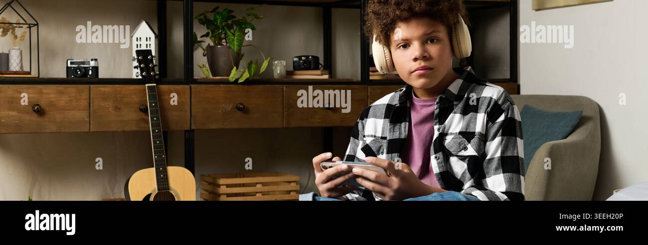 Ein Teenager entspannt sich in einem gemütlichen Wohnzimmer und spielt intensiv mit einer Handkonsole. Stockfoto