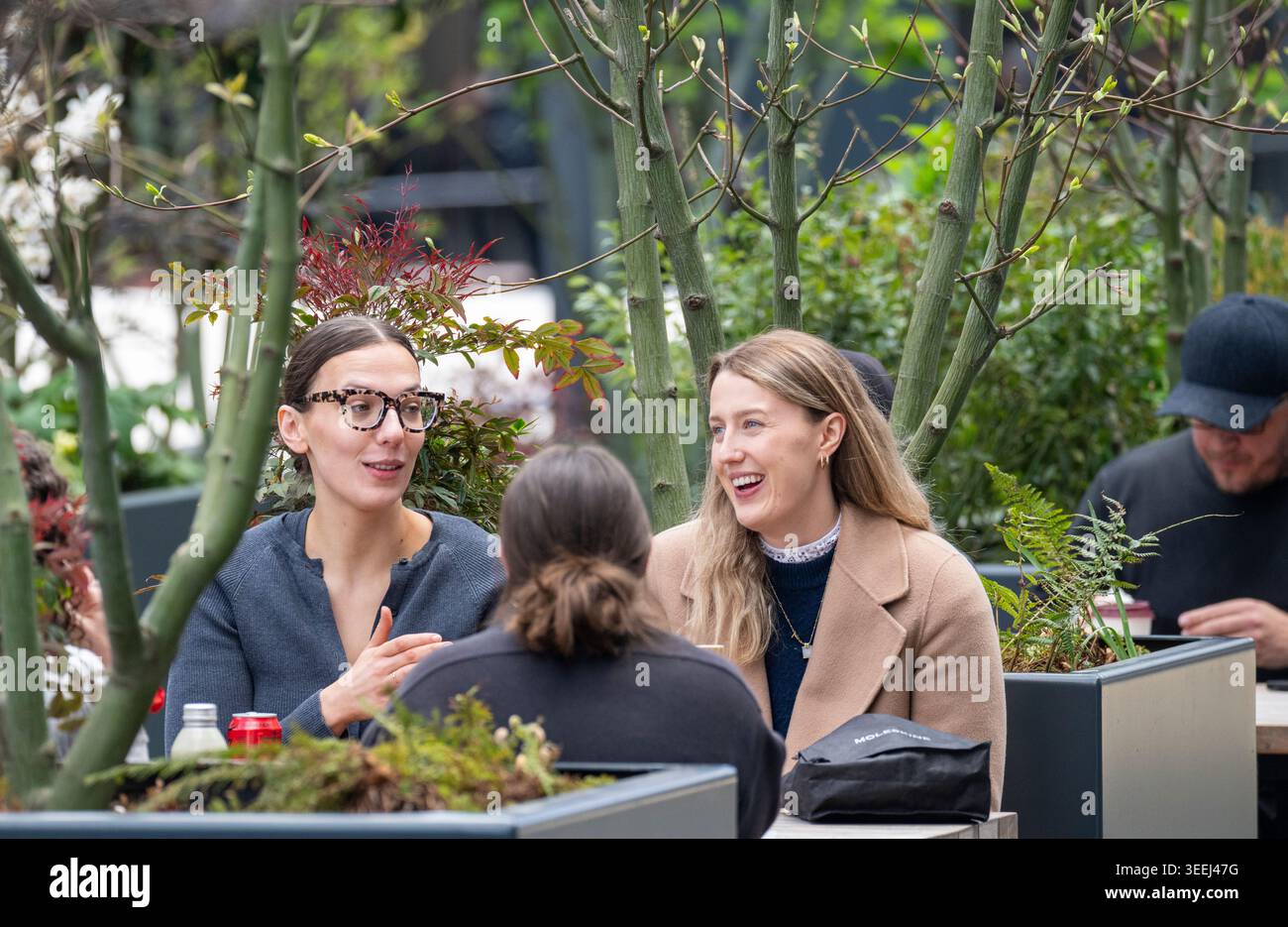 Freunde treffen sich auf einer Terrasse im Freien in Canary Wharf, London. Stockfoto
