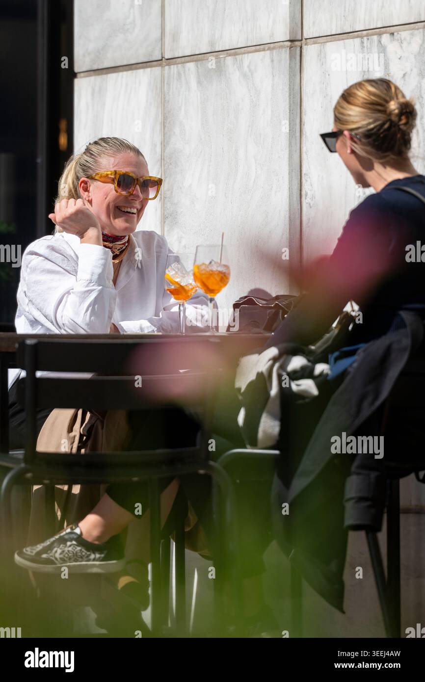 Zwei Frauen genießen Drinks und Gespräche auf einer Außenterrasse des Restaurants in Canary Wharf, London. Stockfoto