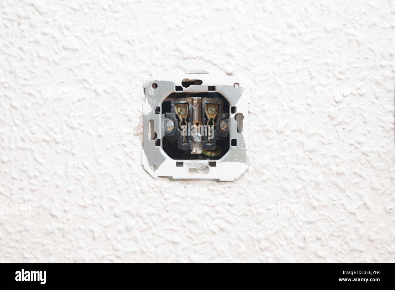 Freiliegende Steckdose mit sichtbaren Drähten, die darauf hinweisen, dass eine Reparatur im Haus erforderlich ist Stockfoto
