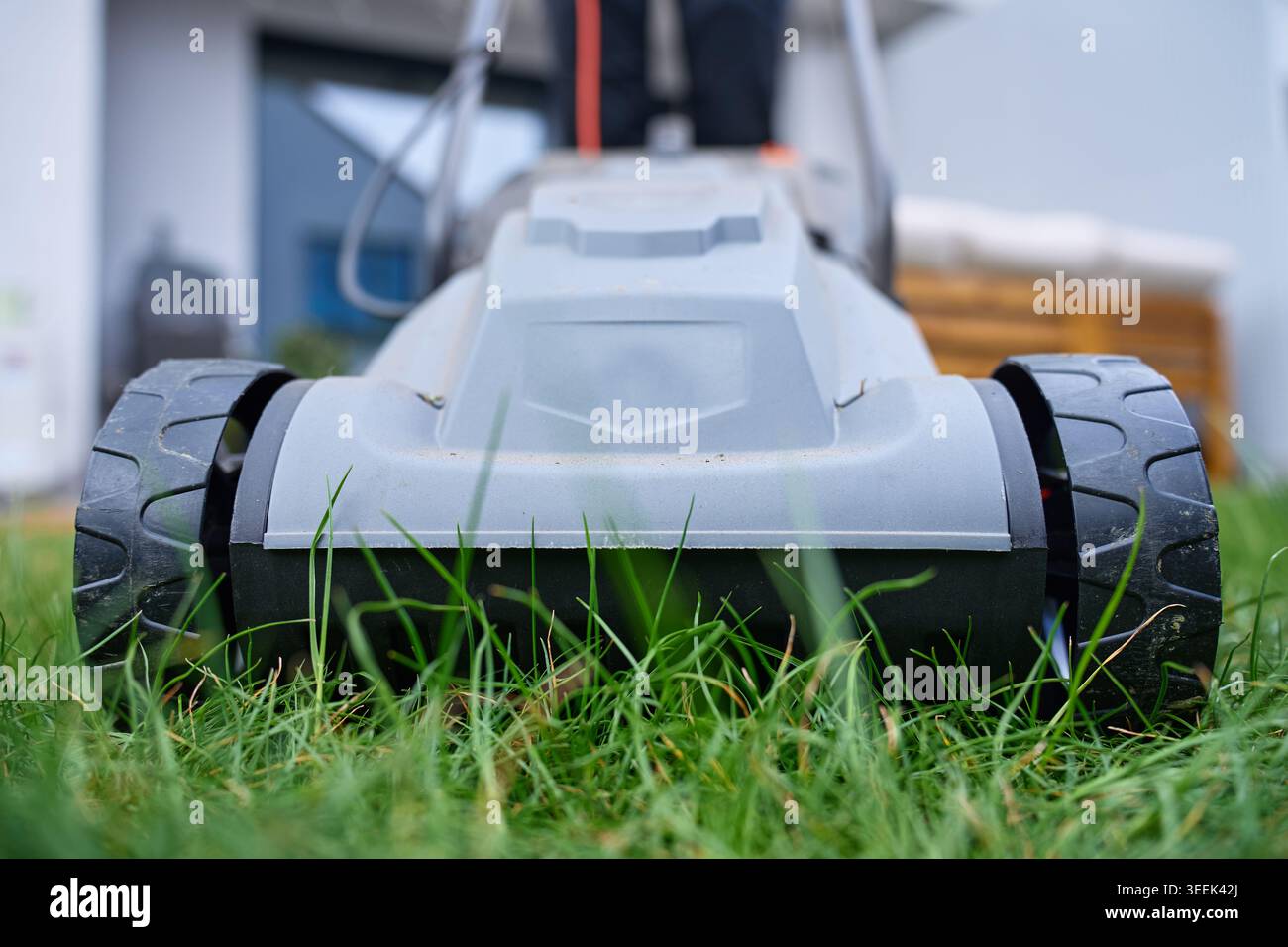 Nahaufnahme der Vorderräder des Rasenmähers auf Gras im Garten im Garten. Konzept für Rasenpflege, Gartenbau und Hauspflege Stockfoto