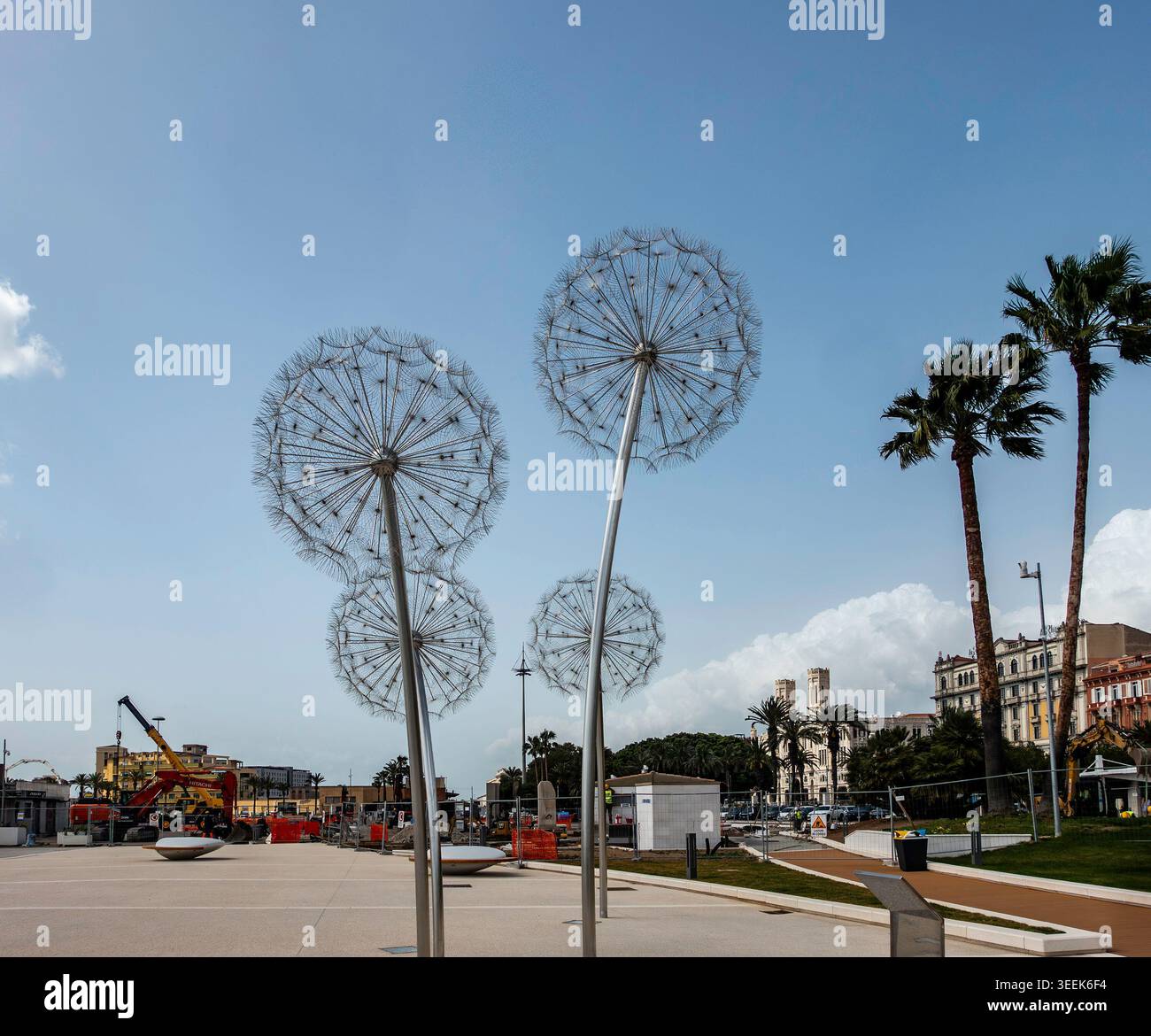 Große Löwenzahnskulpturen aus Metall auf einem öffentlichen Platz in Cagliari, Italien. Baumaschinen und Palmen sind im Hintergrund zu sehen. Stockfoto