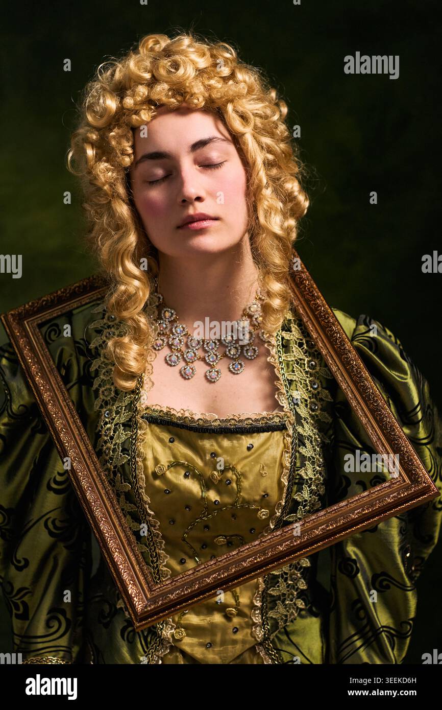 Vertikales Porträt einer jungen Frau, die in historischem Kostüm mit kunstvollem Rahmen posiert und an Kunst und Geschichte erinnert. Ideal für Museumswerbung und Theatermarketing Stockfoto