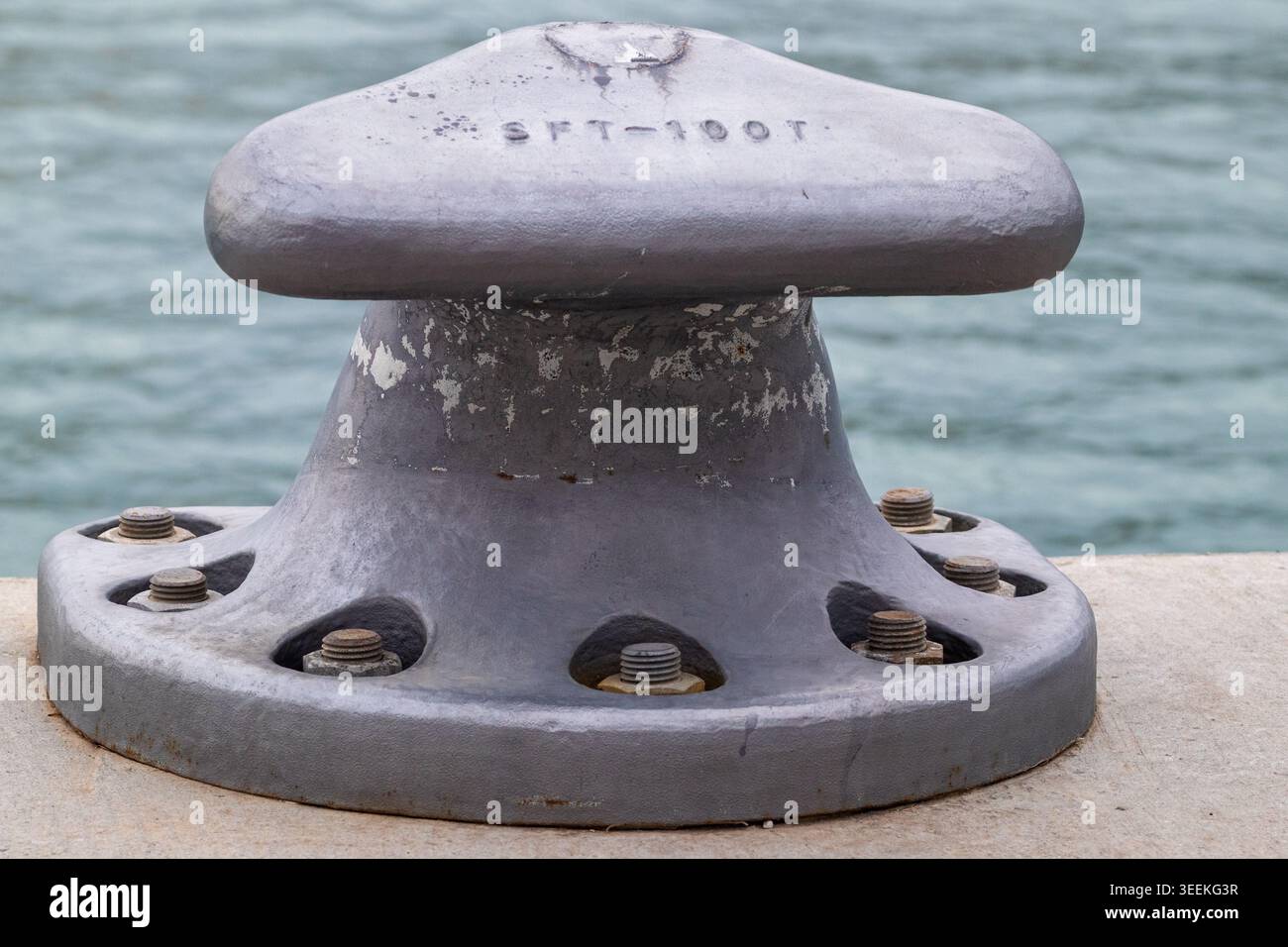 Hochleistungspoller aus Gusseisen, der an einem Betonpier verschraubt ist, um die Sicherheit auf See zu gewährleisten Stockfoto