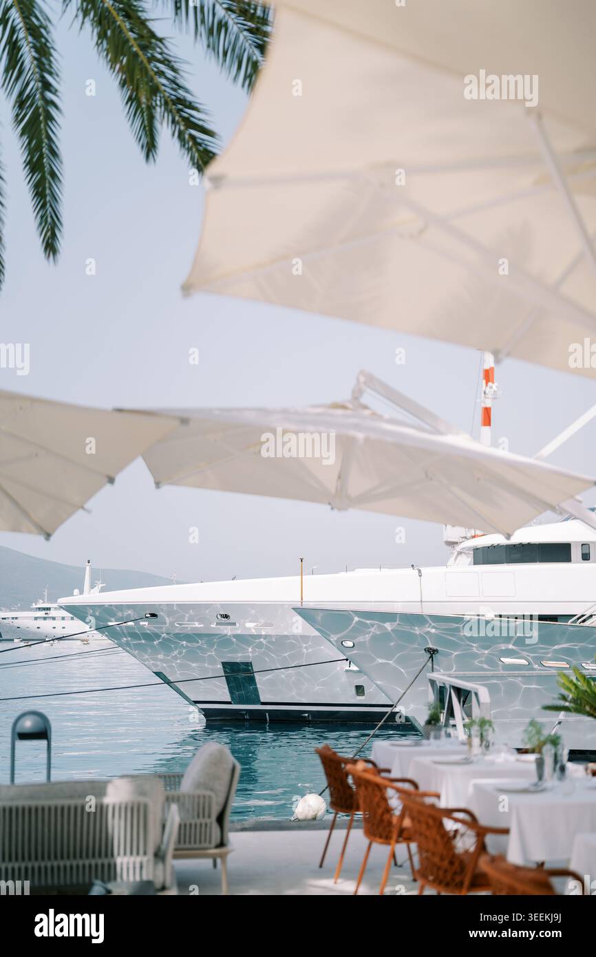 Ruhiges Yachthafen-Ambiente mit Yachten und schattigen Tischen im Freien Stockfoto