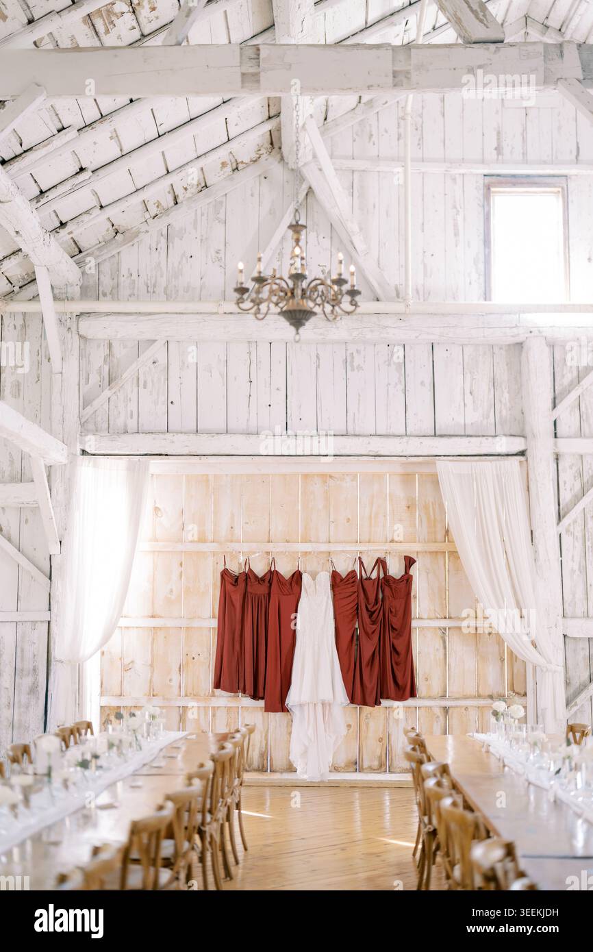 Rustikale Hochzeitseinrichtung. Charmante Holzstühle in der rustikalen Scheune. Ruhige Zeremonie im Landhausstil mit Holzsitzen und weichem Tageslicht Stockfoto