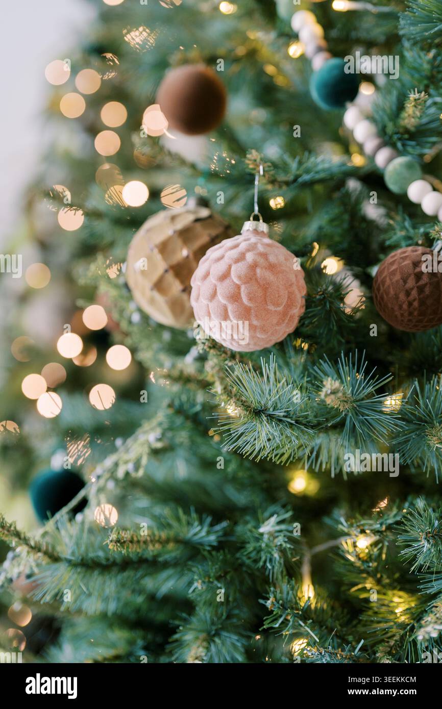 Gemütliche Weihnachtsdekoration. Warm dekorierte Kiefer für Urlaubsambiente. Intimes festliches Ambiente mit Ornamenten und glitzernden Lichtern Stockfoto