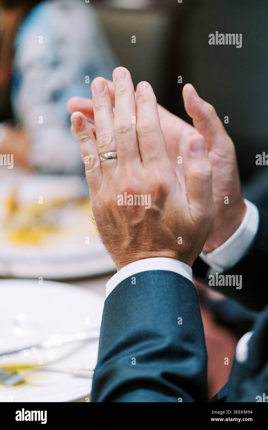 Großaufnahme der Hände, die zur Feier klatschen, mit eleganter Kleidung und Ambiente-Glühen Stockfoto