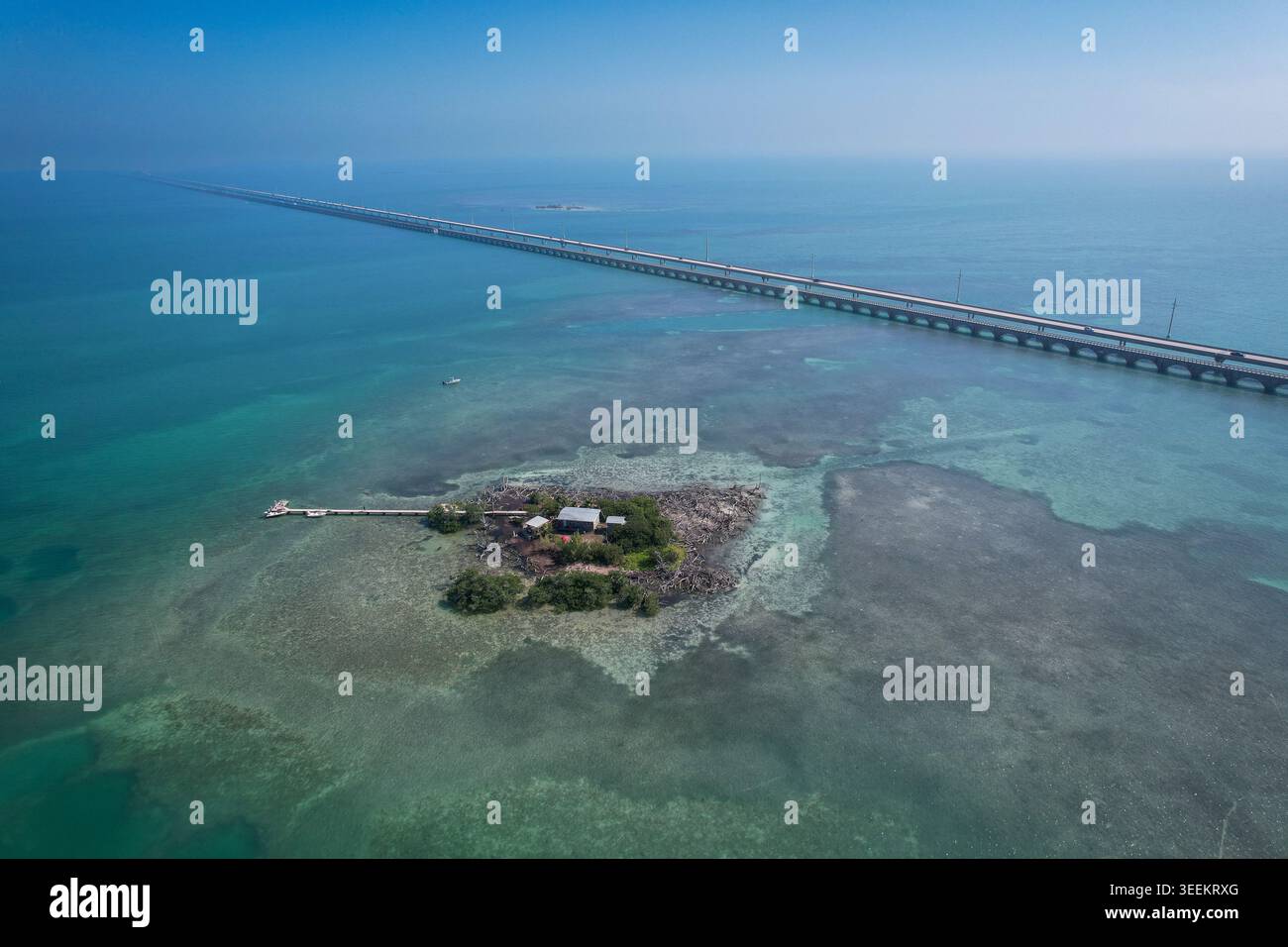 Blick aus der Vogelperspektive auf den Overseas Highway, der sich über türkisfarbenes Wasser in der Nähe einer kleinen privaten Insel mit Dock und Gebäude in Key Largo, Florida, Uni erstreckt Stockfoto