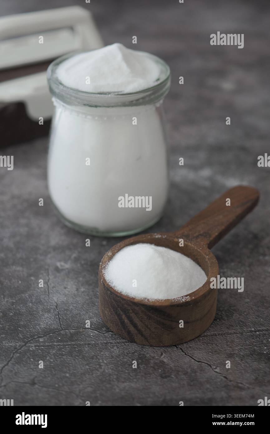 Backnatron Pulver in einem Glas und eine Holzlöffel auf grauer Oberfläche Stockfoto