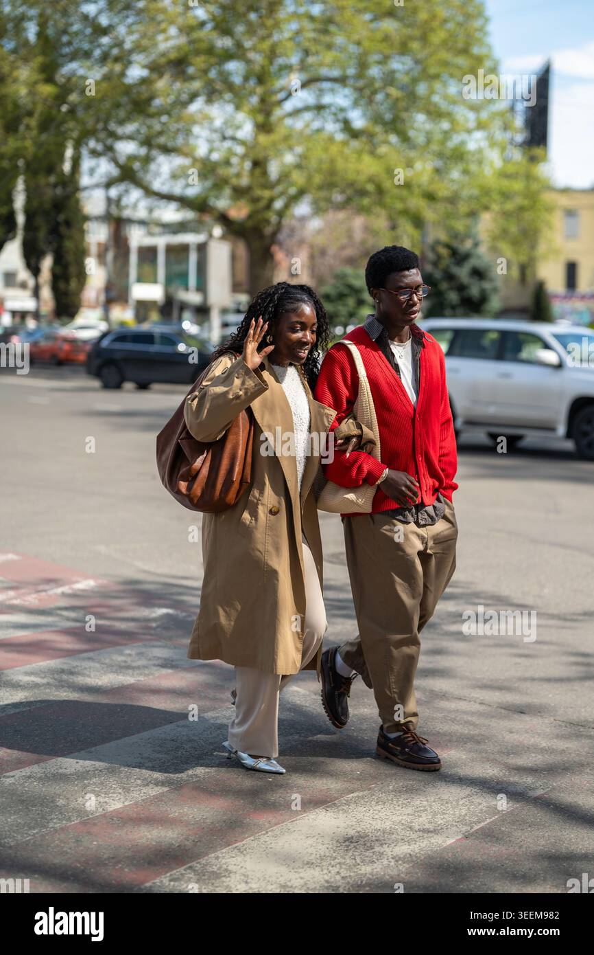 Fröhliche Leute befreundet afroamerikanische Männer und Frauen, die durch die Straßen der Stadt laufen und sich unterhalten. Stockfoto