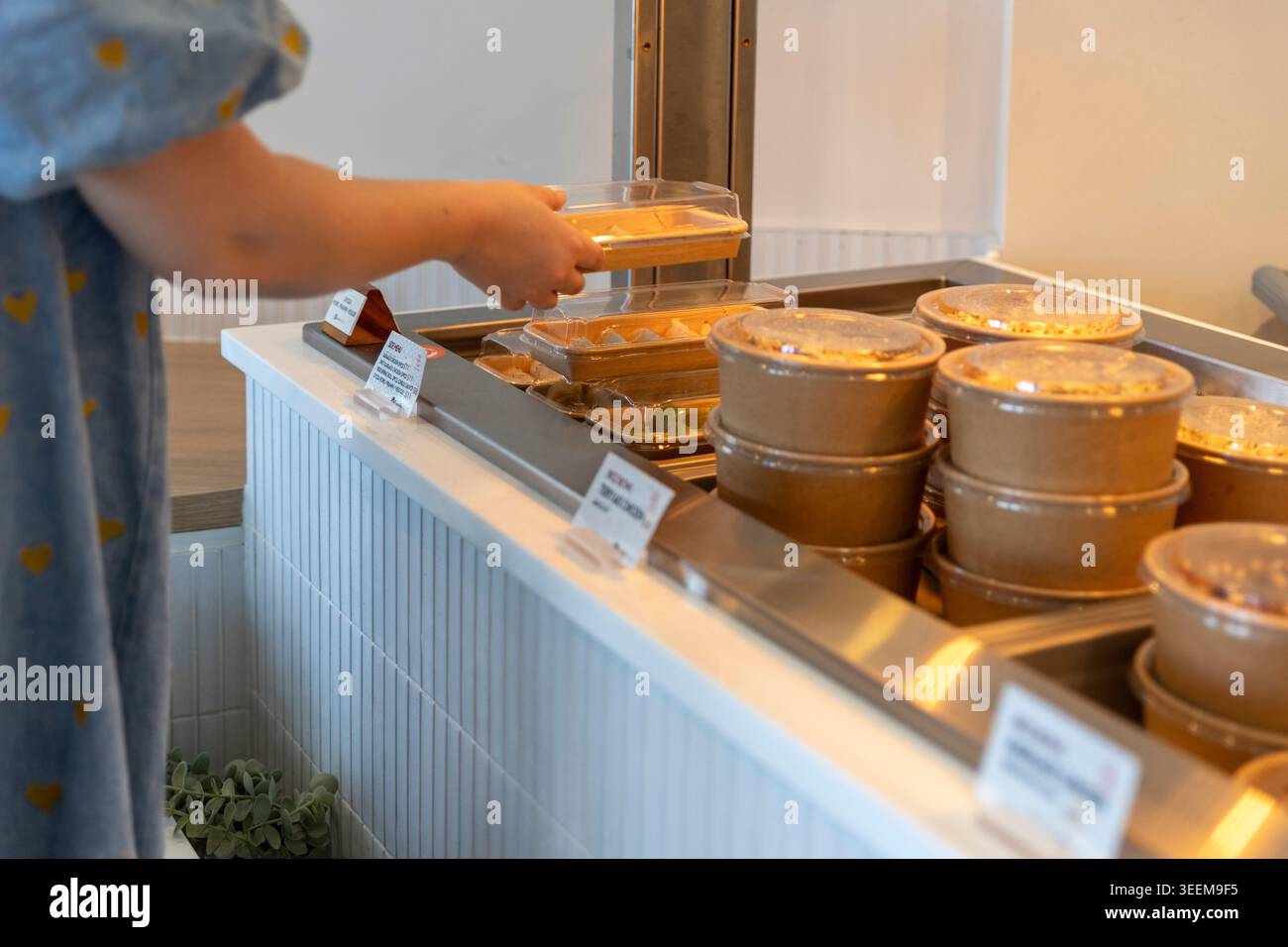 Kunde, der nach einem verpackten Sushi-Tablett aus einem modernen Imbissladen in Queensland, Australien, sucht. (2025) Stockfoto