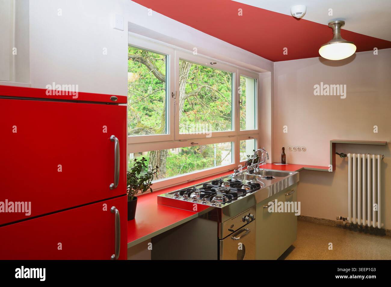 Die originalgetreu restaurierte Bauhaus-Küche im Haus Rabe in Zwenkau mit markanten roten Schränken, roter Decke und großem Fenster Stockfoto