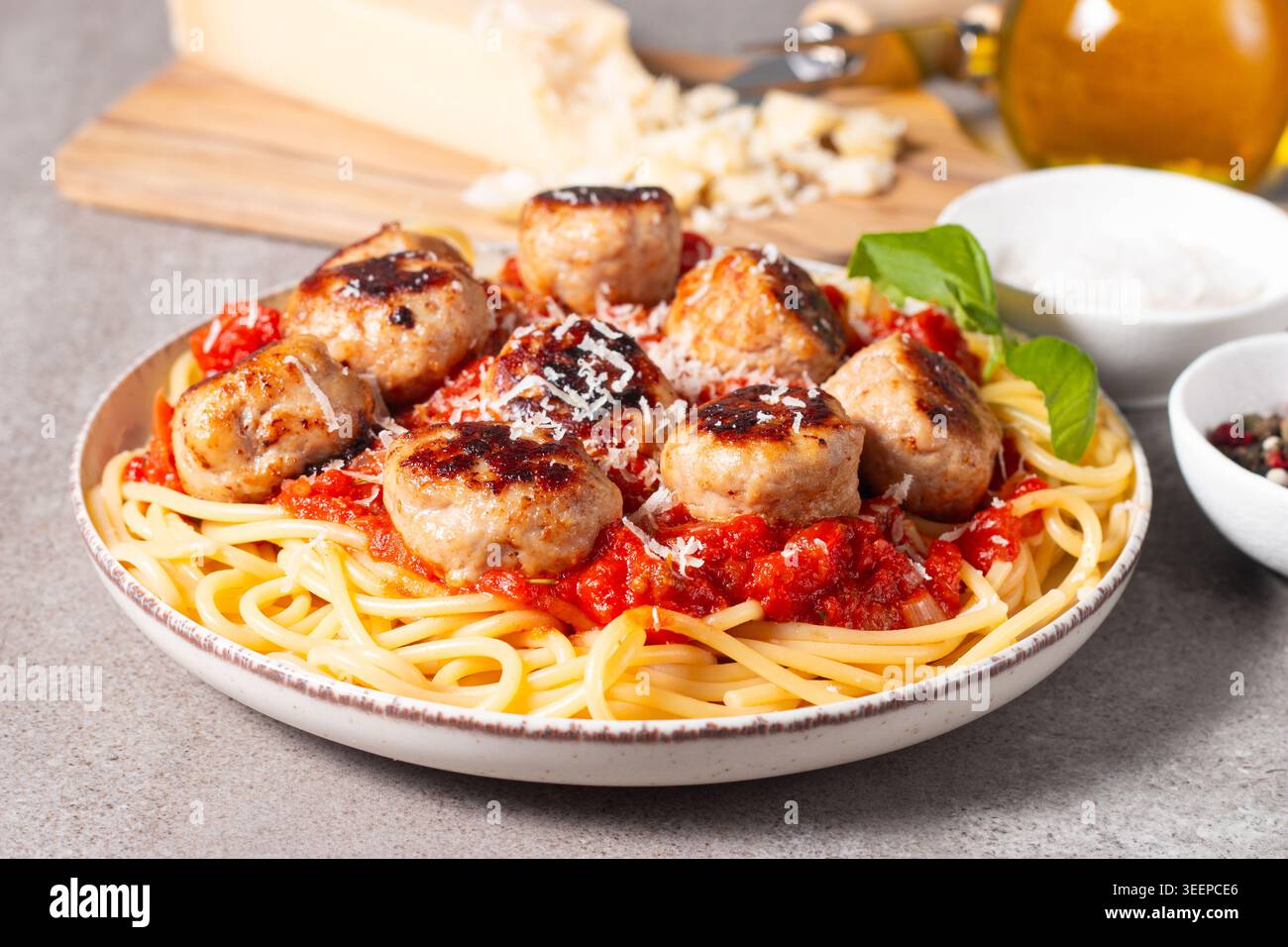 Ein Teller mit klassischen Spaghetti, garniert mit gebräunten Fleischbällchen und reichhaltiger Tomatensauce auf einem leichten Keramikgericht. Stockfoto