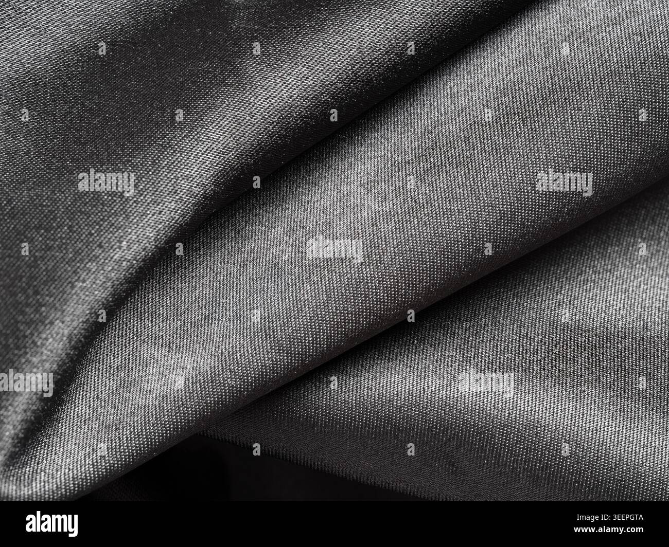 Dunkelgrauer, glänzender Stoff, der elegante und luxuriöse Falten schafft und einen glatten und weichen Textilinhalt hervorhebt Stockfoto