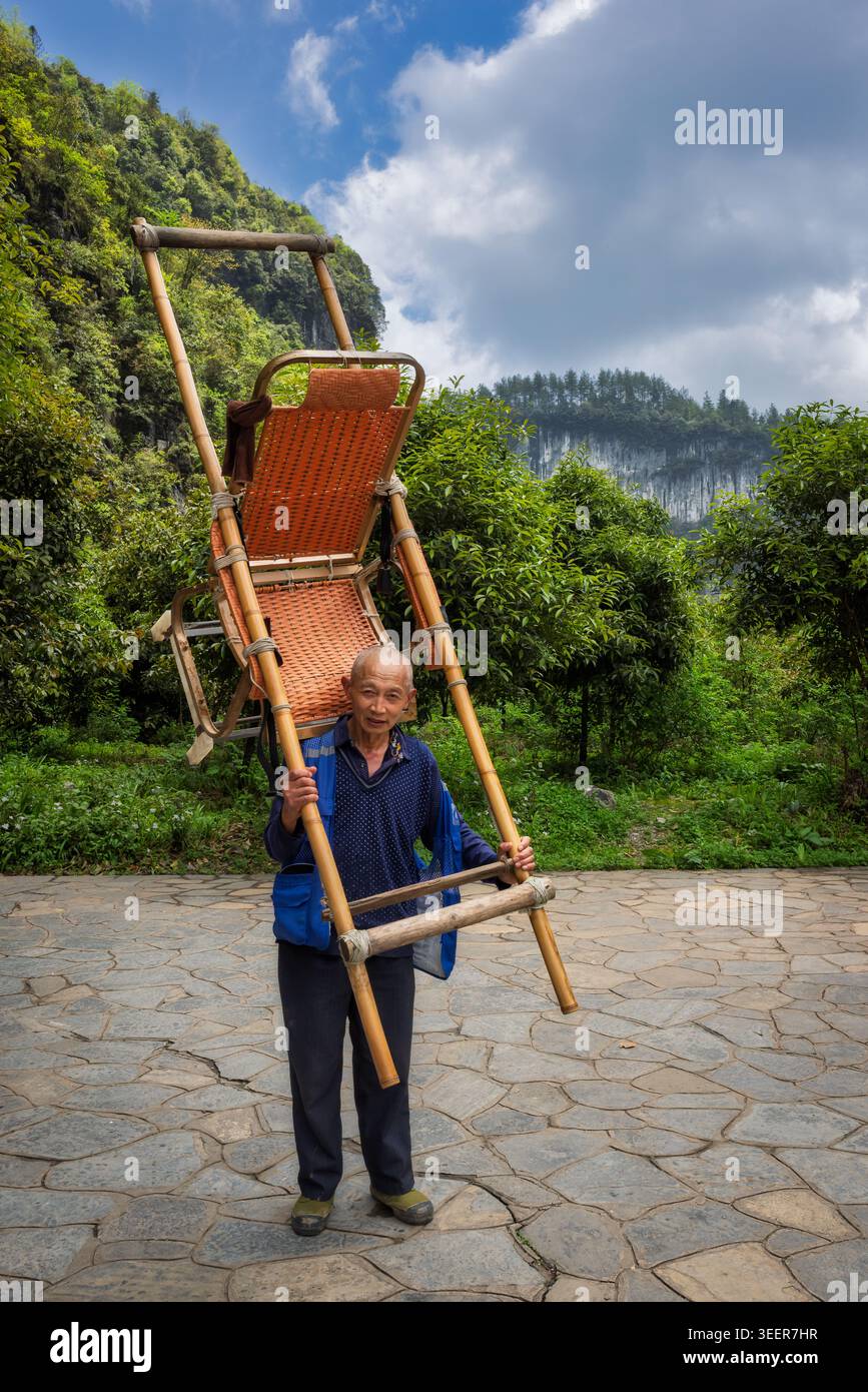 Ein älterer Mann mit einem Stuhl, Wulong, China Stockfoto