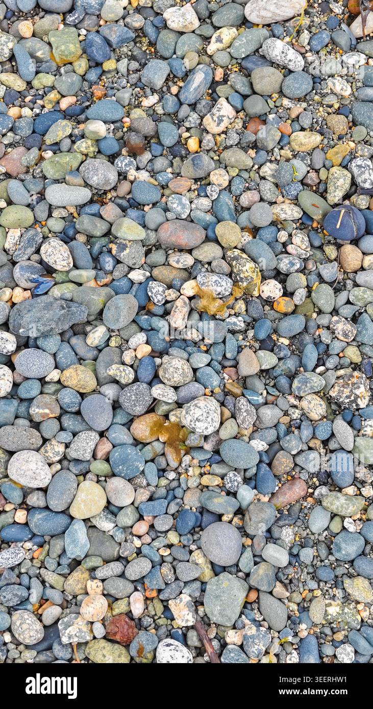 Die rahmenfüllende Aufnahme zeigt eine Reihe von glatten Steinen. Erdtöne, einschließlich Blau- und Brauntöne, dominieren mit Texturen, die Tiefe verleihen. Ideal für Backg Stockfoto