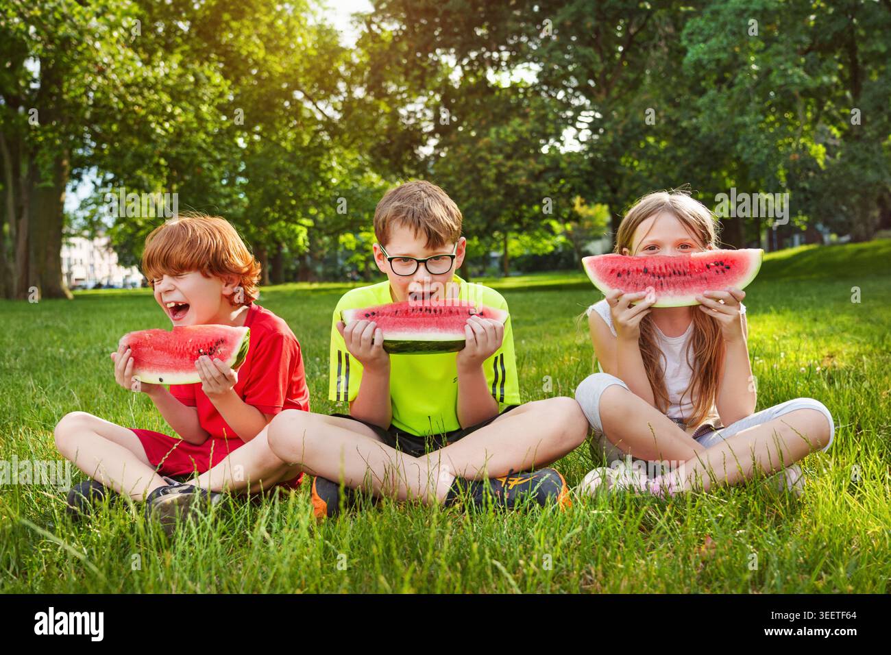 Gruppe von Kindern isst Wassermelone im Sommer draußen. Genießen Sie sonnige Tage mit süßem Wasselmelon. Stockfoto