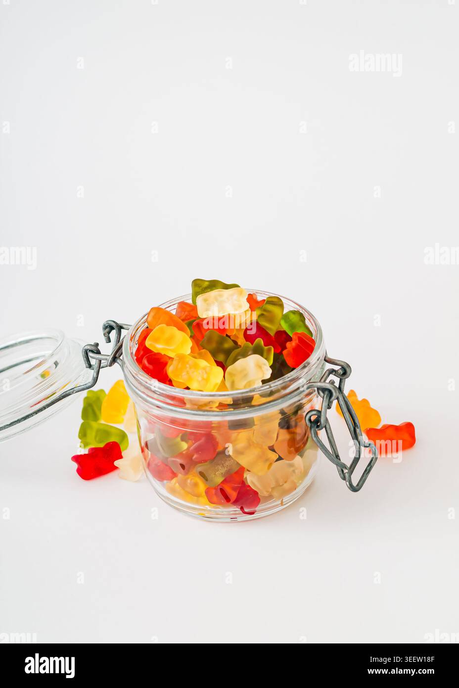 Bunte Gummibonbons in einem Glas auf weißem Hintergrund. Trendiges Gummikonzept. Gelee-Süßigkeiten-Ästhetik. Stockfoto